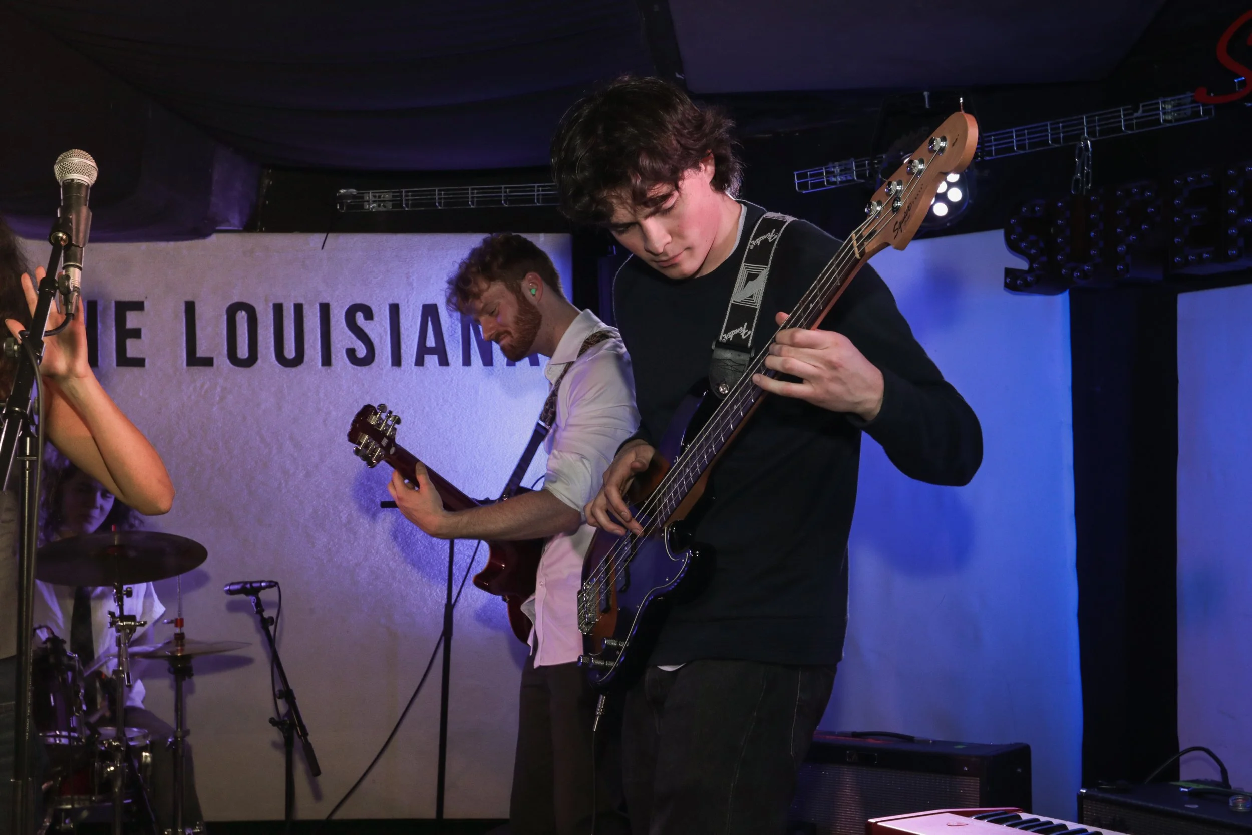 Two musicians playing electric and acoustic guitars on stage during a live performance at The Louisiana