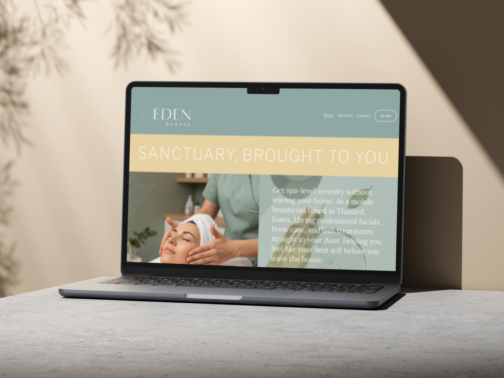 A laptop on a white table displaying a website for Eden Beauty, with a background image of a woman receiving a facial treatment in a spa-like setting.