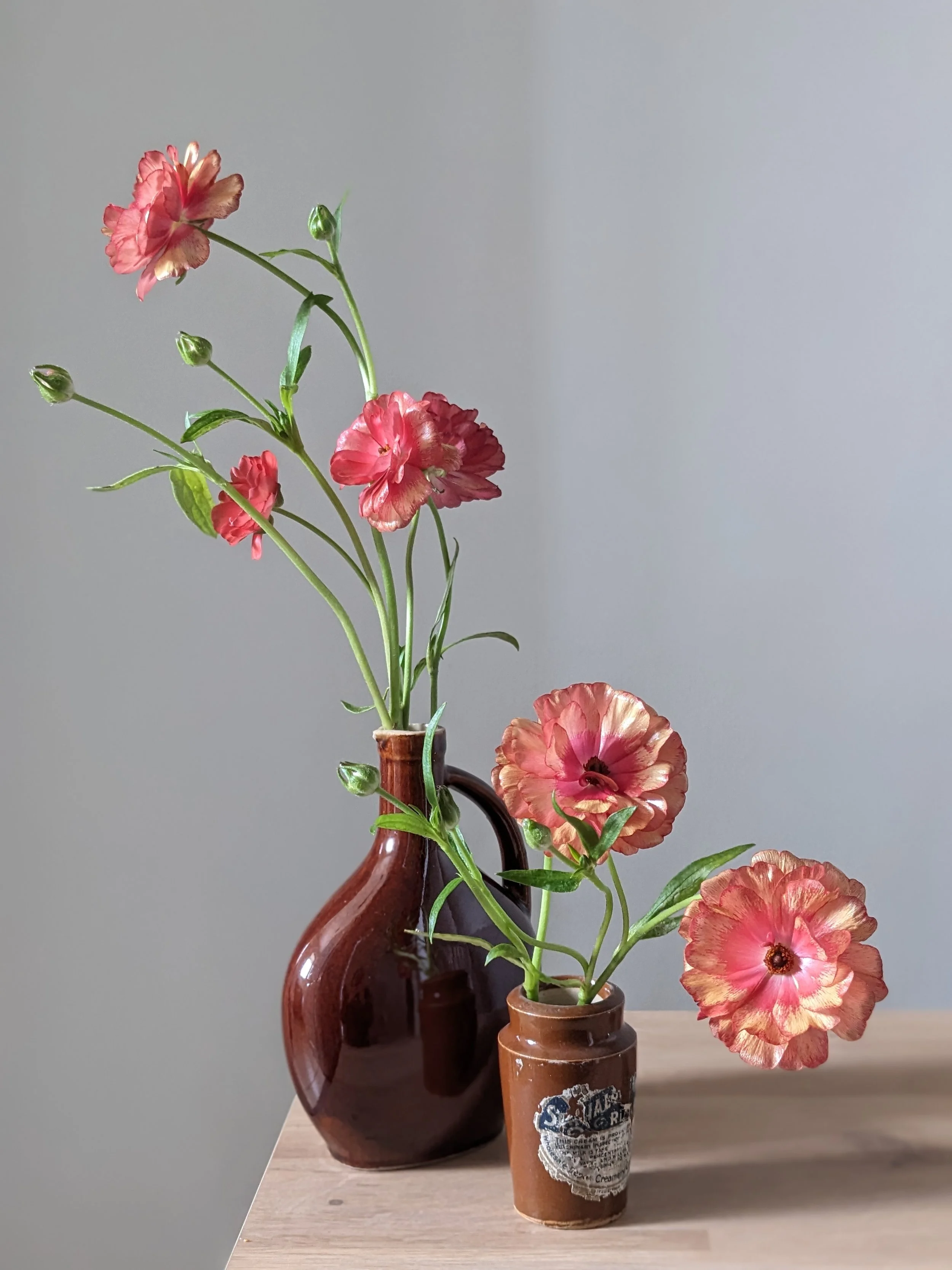 Pink and peach butterfly ranunculus in brown vases