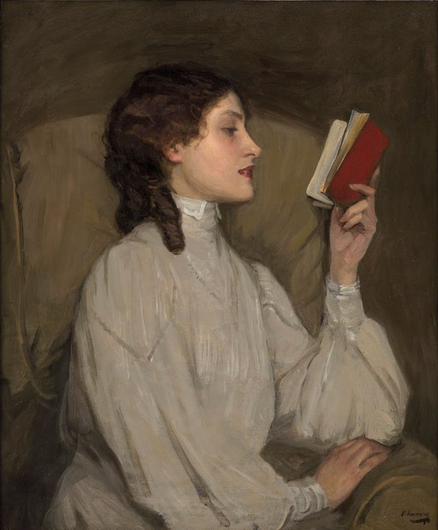 A woman with dark brown hair in a braid, wearing a white high-neck blouse, sitting and reading a small red book, against a brown background.
