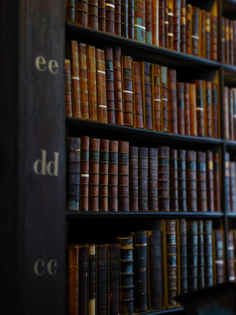 Bookshelves filled with old, leather-bound books in a library.
