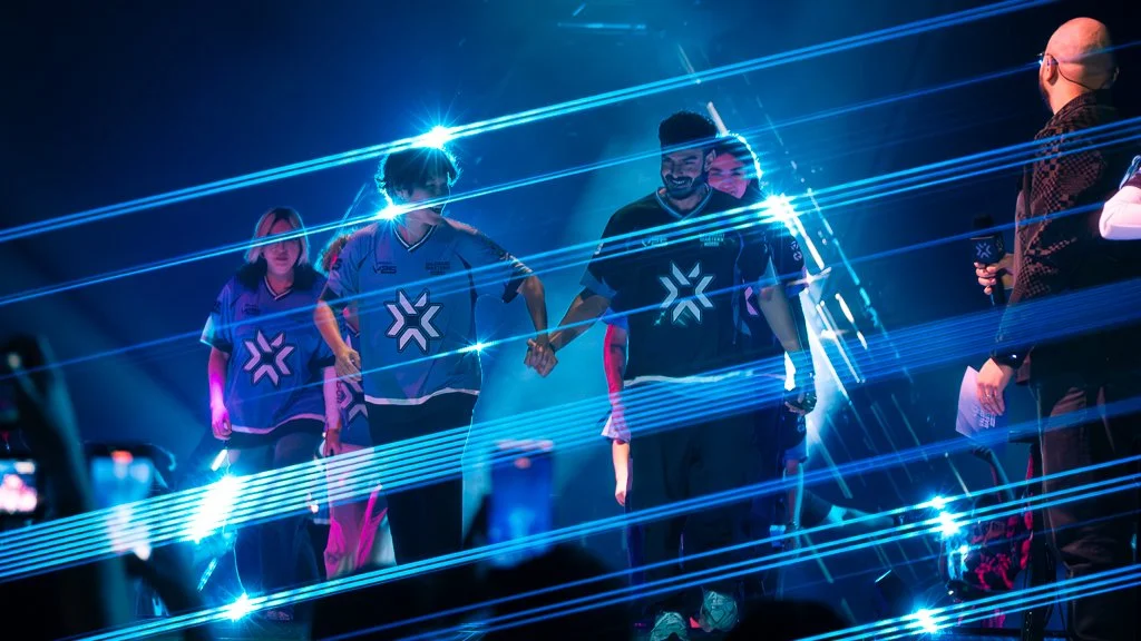 Tarik & Disguised Toast wearing Masters Toronto jersey holding hands in a dark, brightly lit gaming arena with blue laser lights.