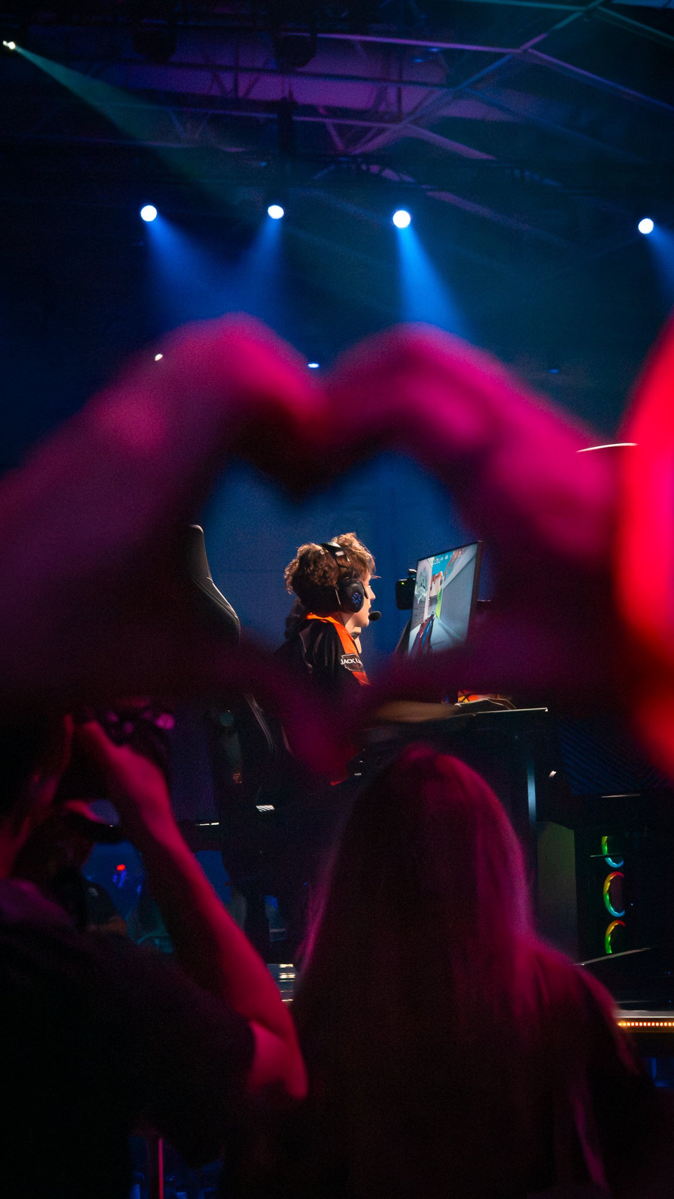 Boaster Valorant Professional Esports player at VCT Masters Toronto, illuminated by stage lights, with a heart shape formed by a person’s hands framing the scene.