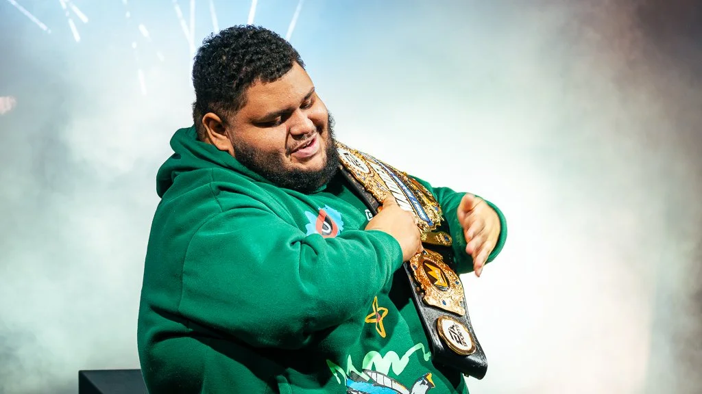 Jonbeast Madden Professional holding a Madden NFL 26 championship belt, smiling and holding a championship belt over his shoulder.