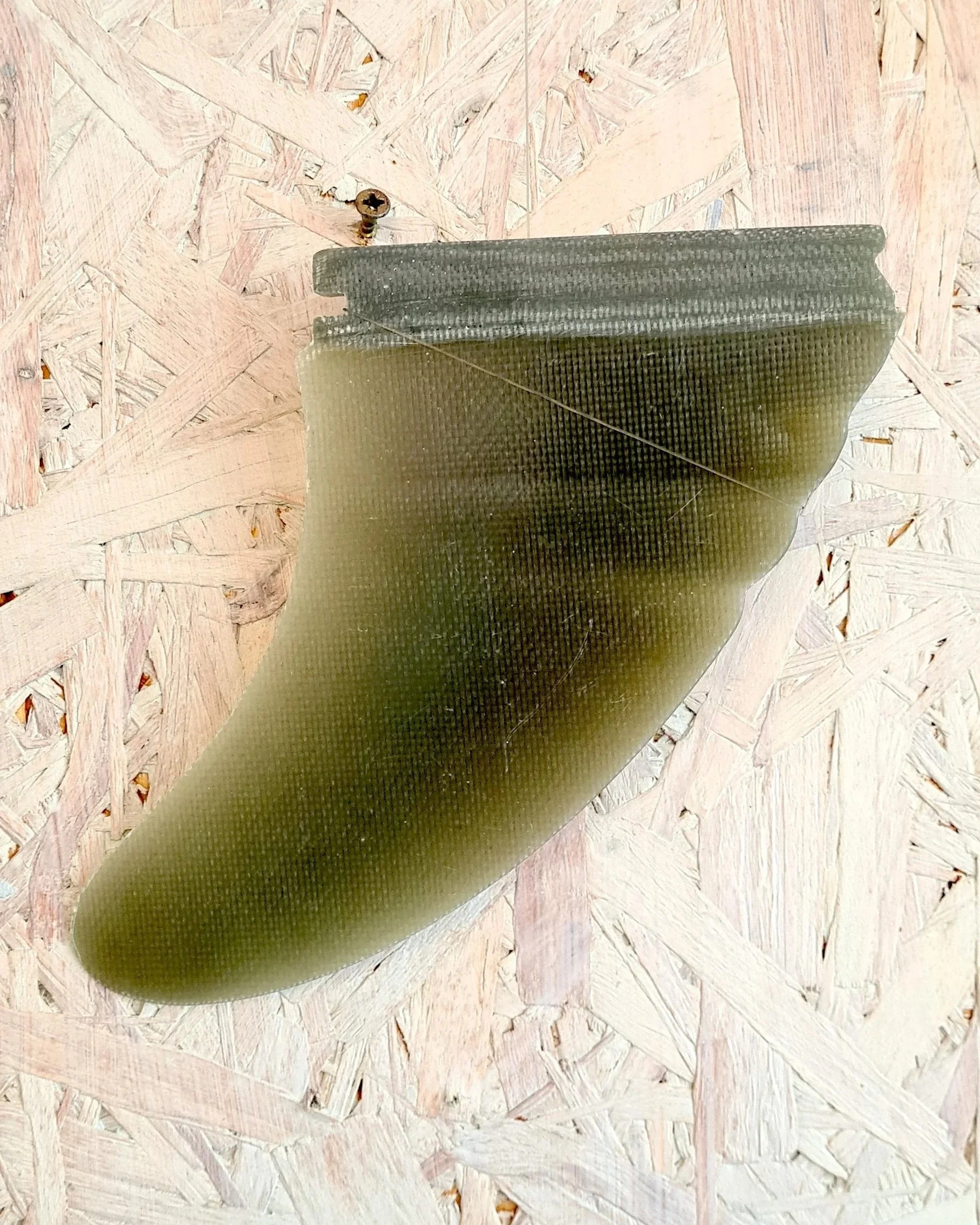 Close-up of the wavy leading edge and base of a hand-foiled twin fin by Sam Heaton, olive-green marbled vinylester with carbon layup