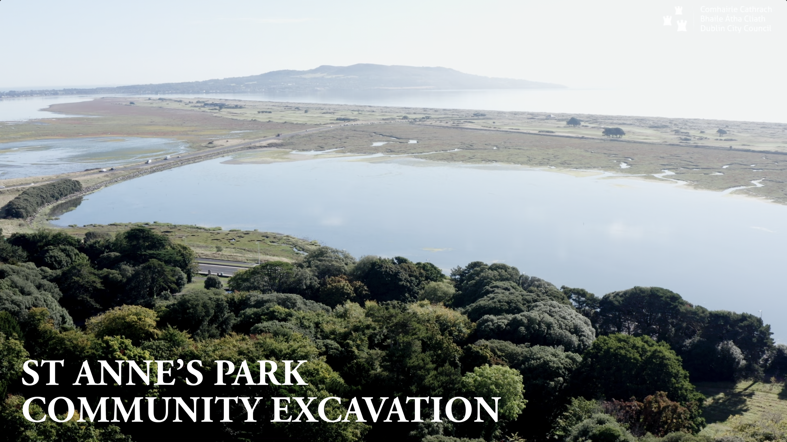 Aerial view of St. Anne's Park with a large lake, green trees, and surrounding landscape, during daytime.