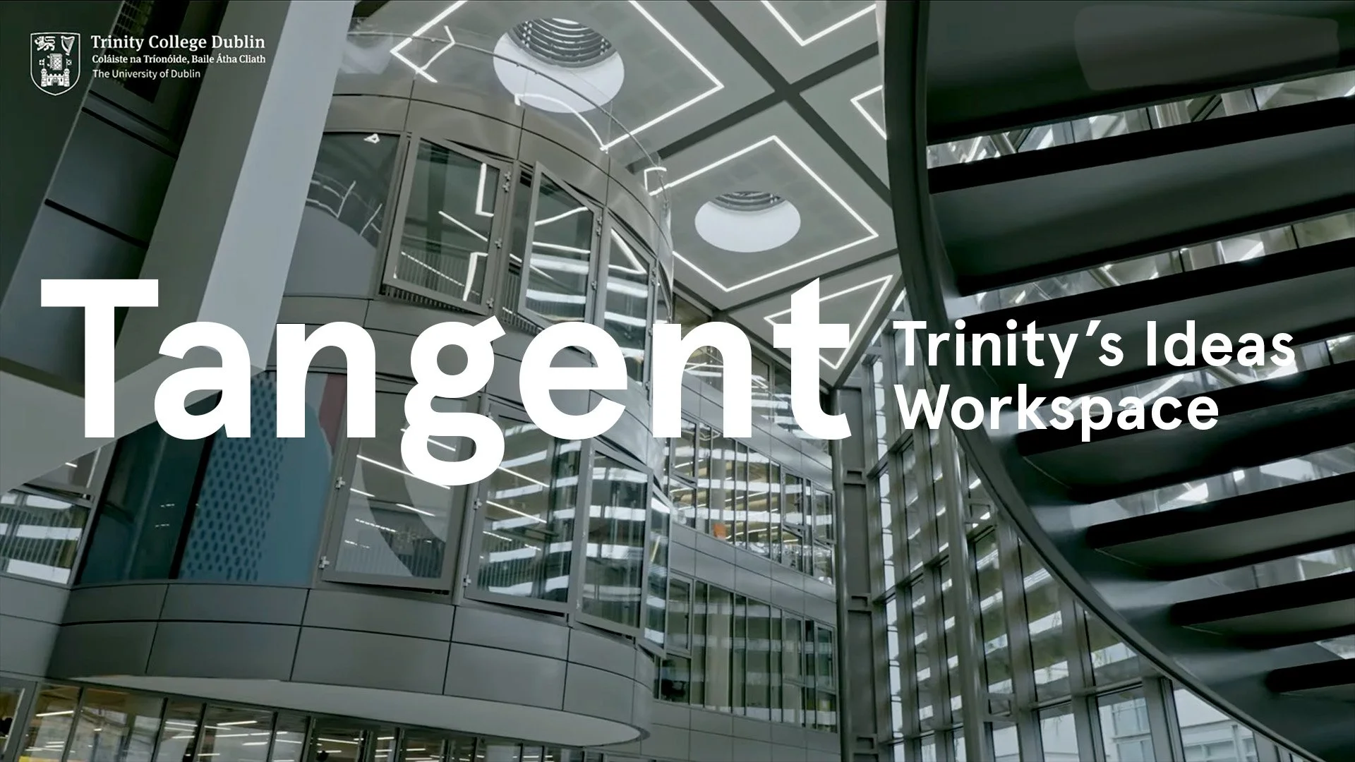 Interior view of Trinity College Dublin's modern workspace with glass walls, metal staircase, and geometric lighting.