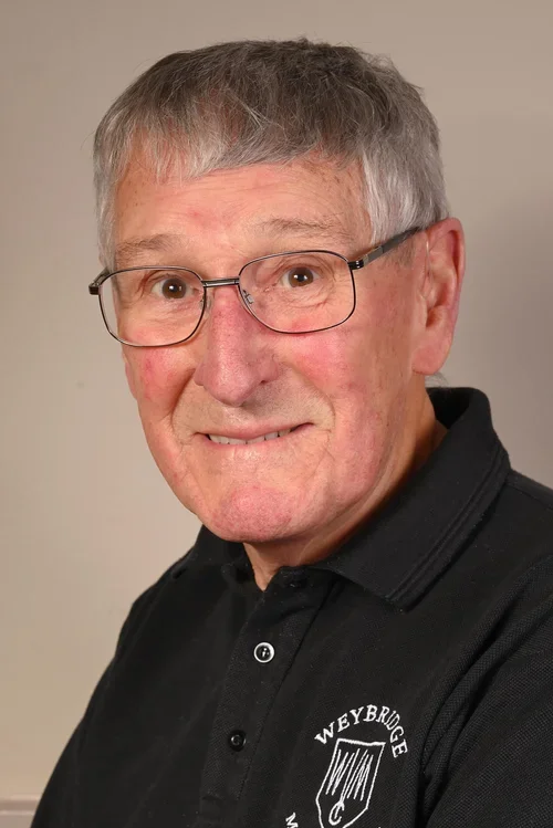 A smiling older man with gray hair and glasses, wearing a black polo shirt with the Weyerbridge logo, against a neutral background.