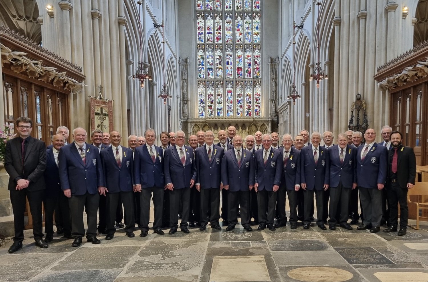 Group of men in suits posing inside a church with stained glass windows.