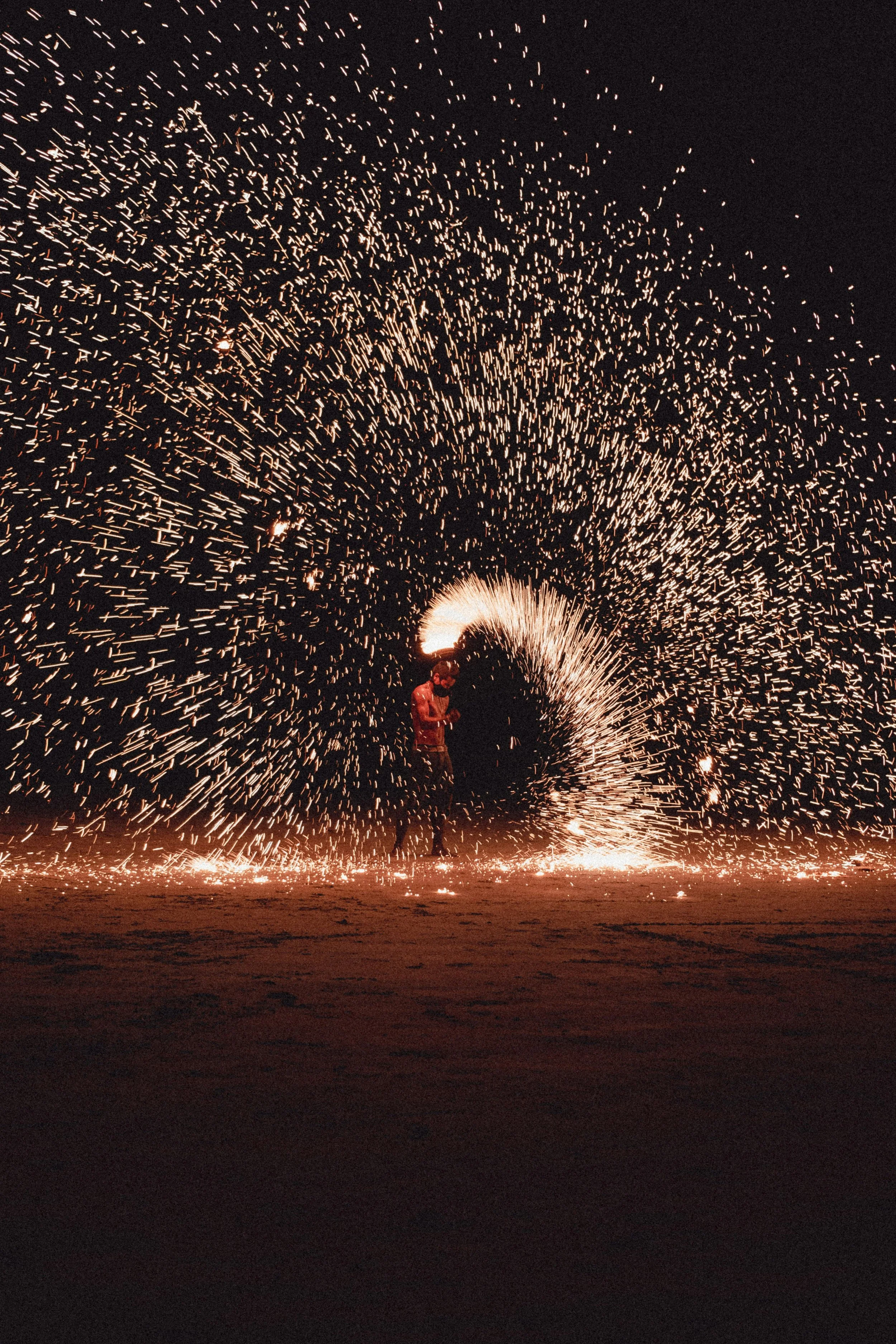 Person spinning a fire torch creating sparks in a circle at night.