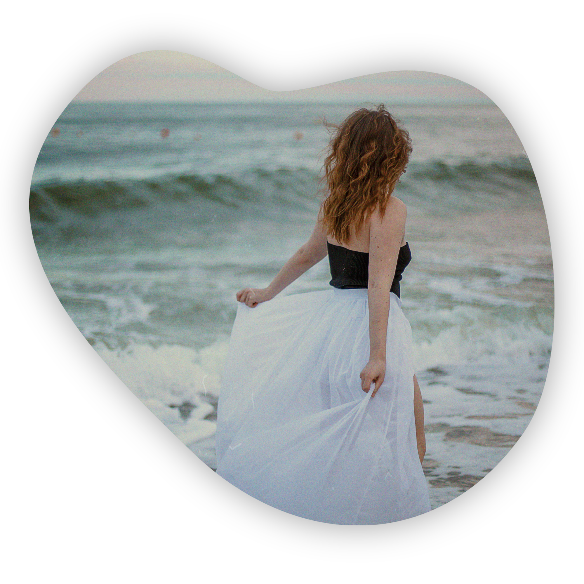 Woman in flowing white skirt by the sea