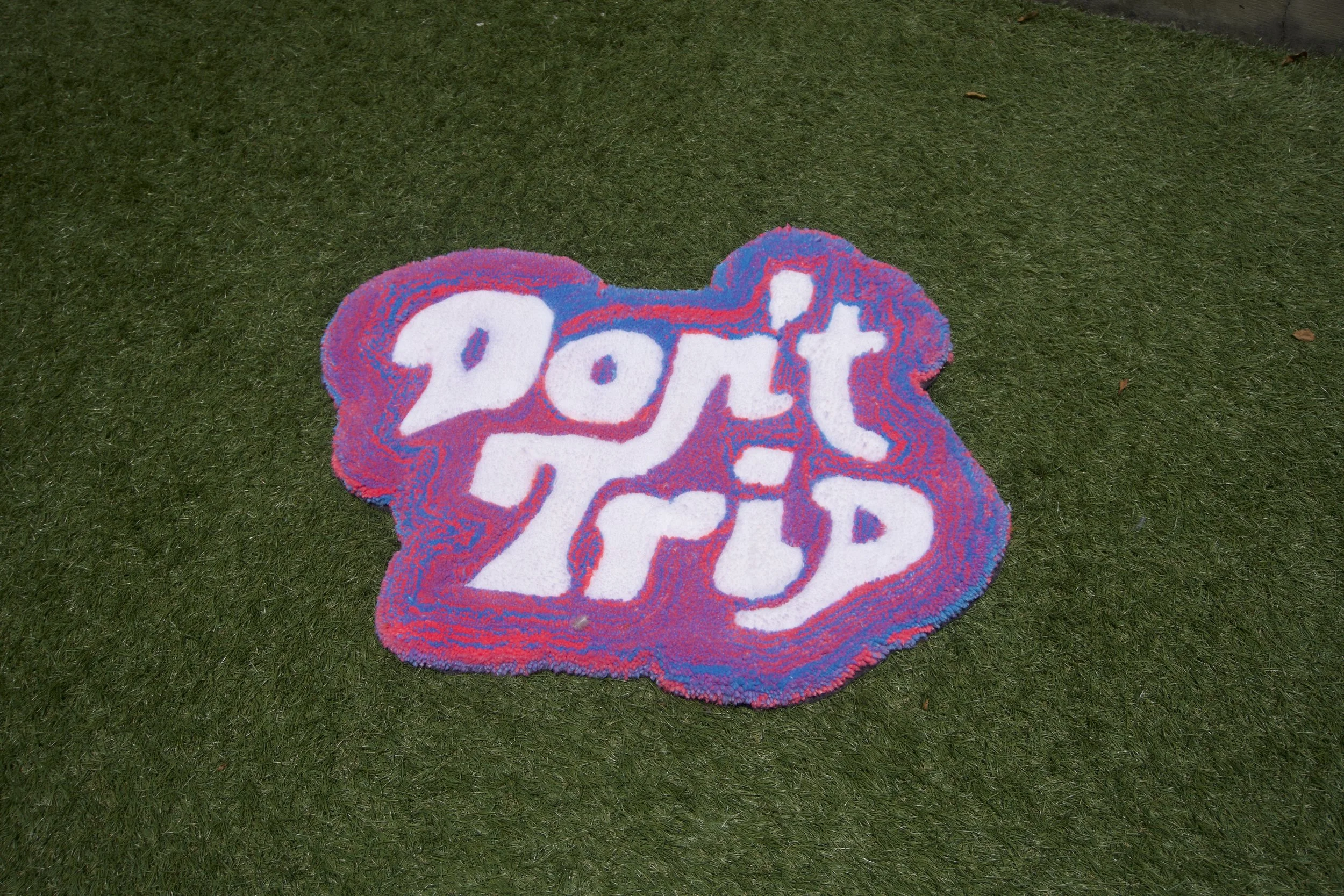 Colorful woven rug on green grass with the words 'Don't Stop' in large white and red letters.