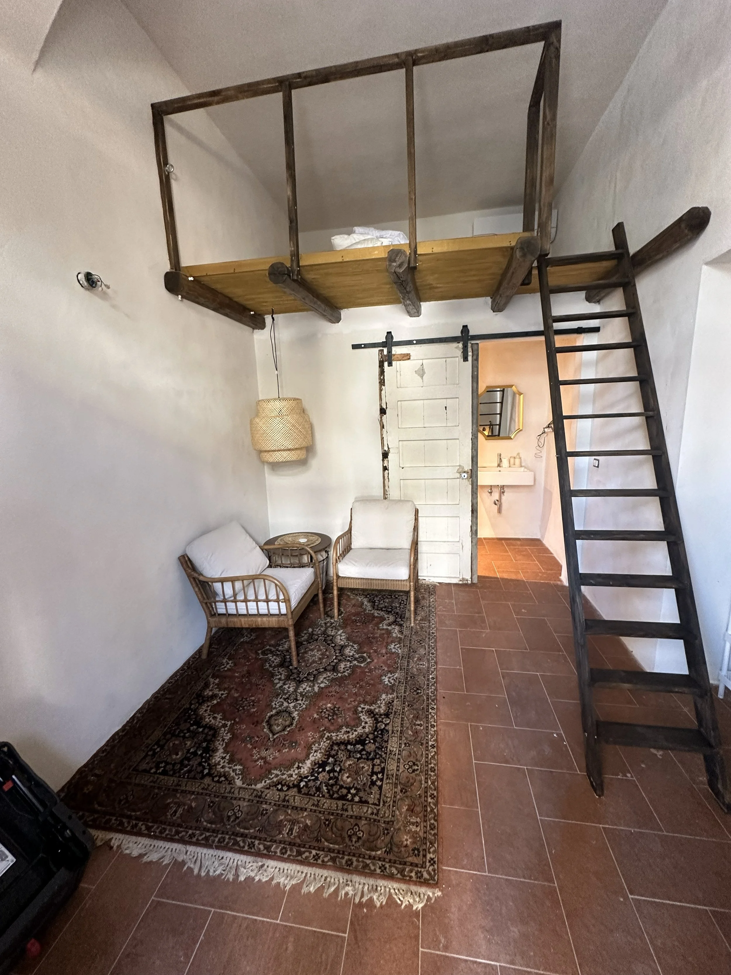Bright guest room with a loft bed and a seating area at Tacasa in Riposto, Sicily.