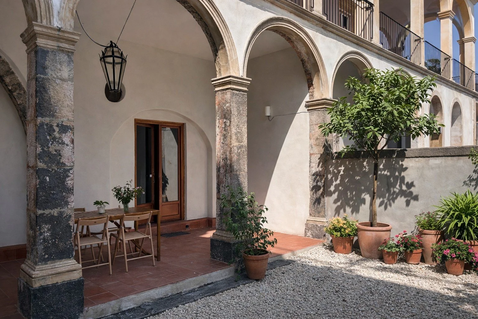 Courtyard with stone arches and outdoor seating at Tacasa in Riposto, Sicily.