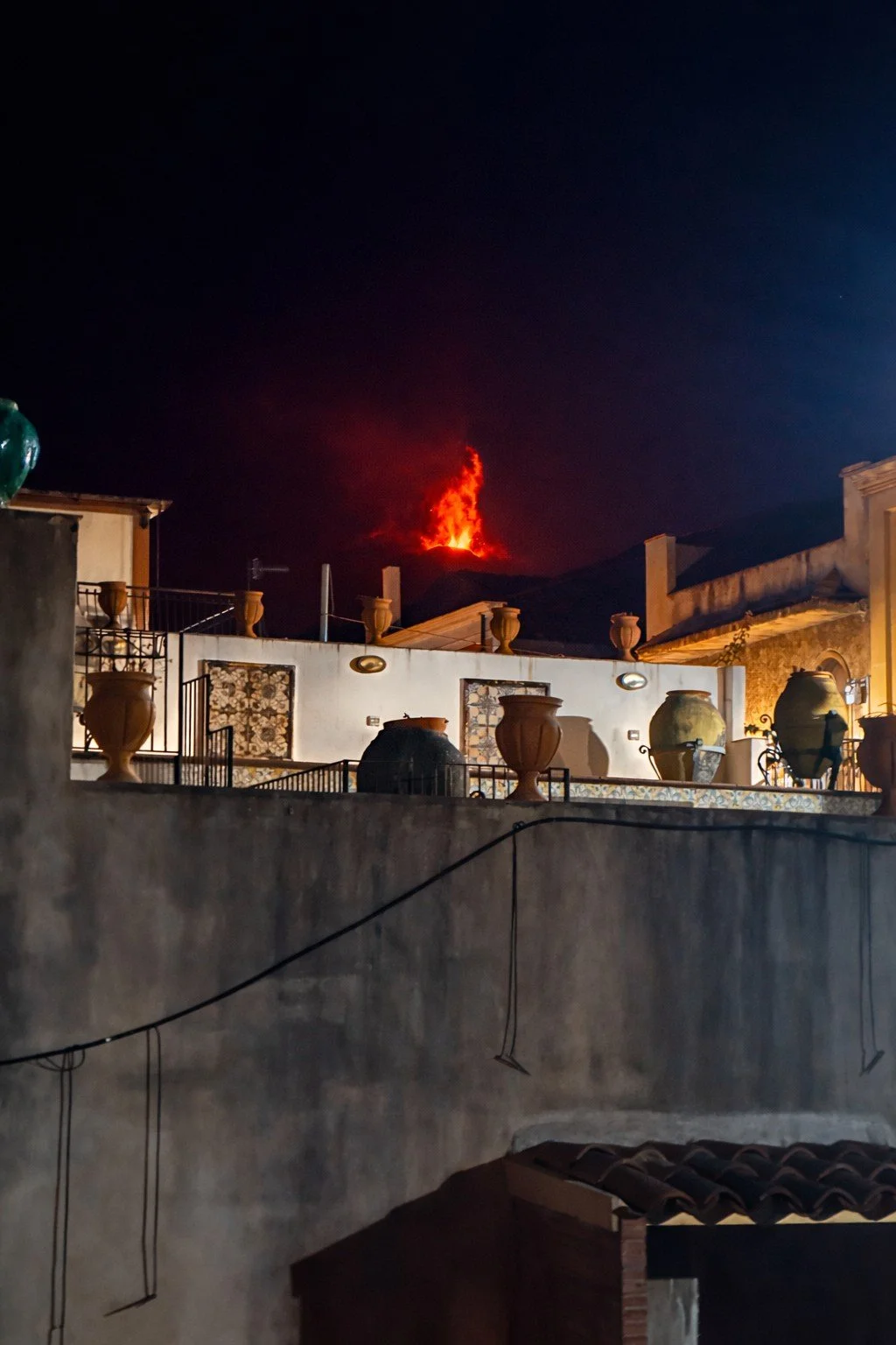 View of Mount Etna erupting at night, seen from a terrace in Riposto, Sicily.