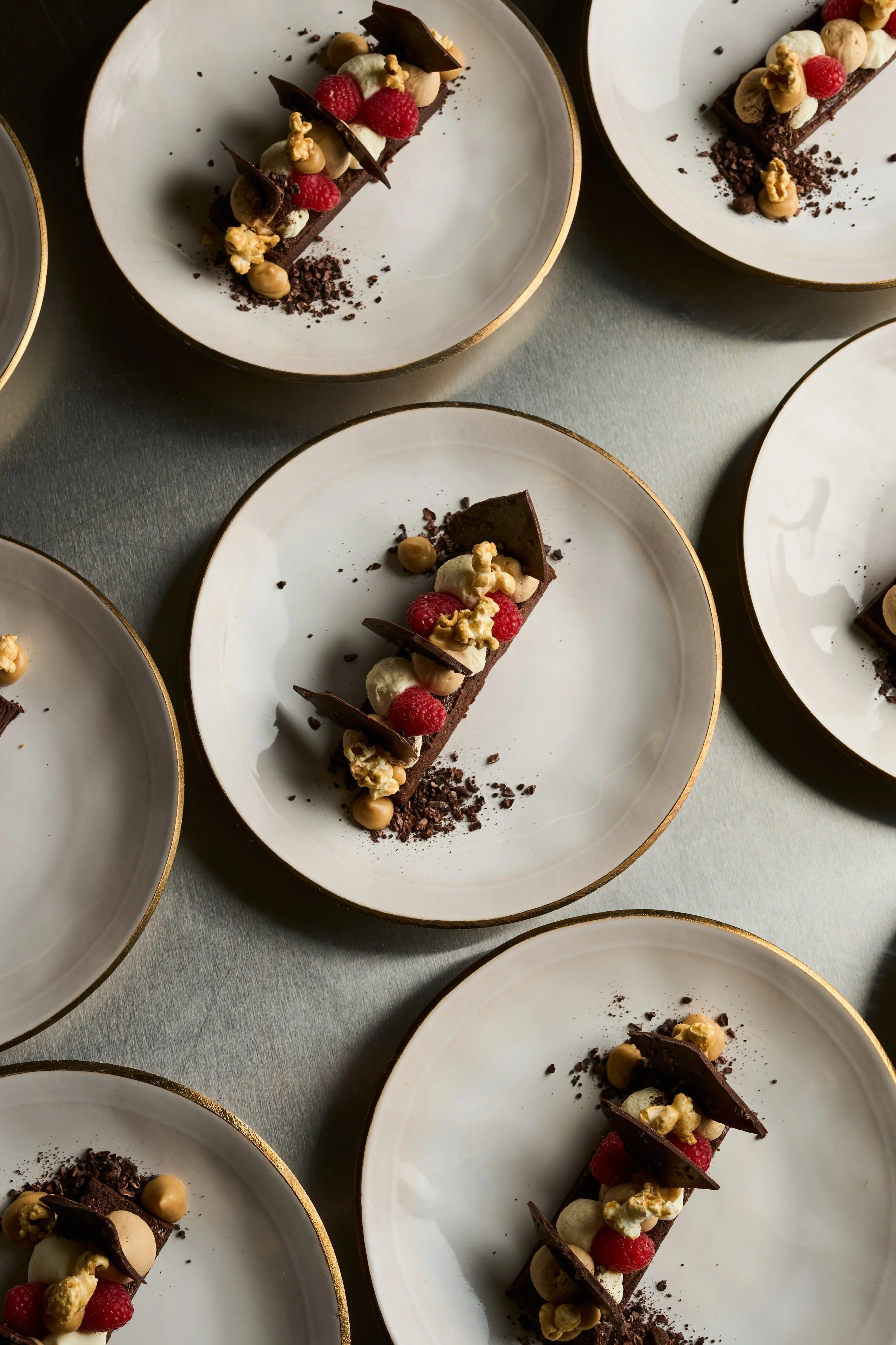Mehrere Dessertteller mit Schokoladenkuchen, Beeren, Popcorn und Dekorationen.