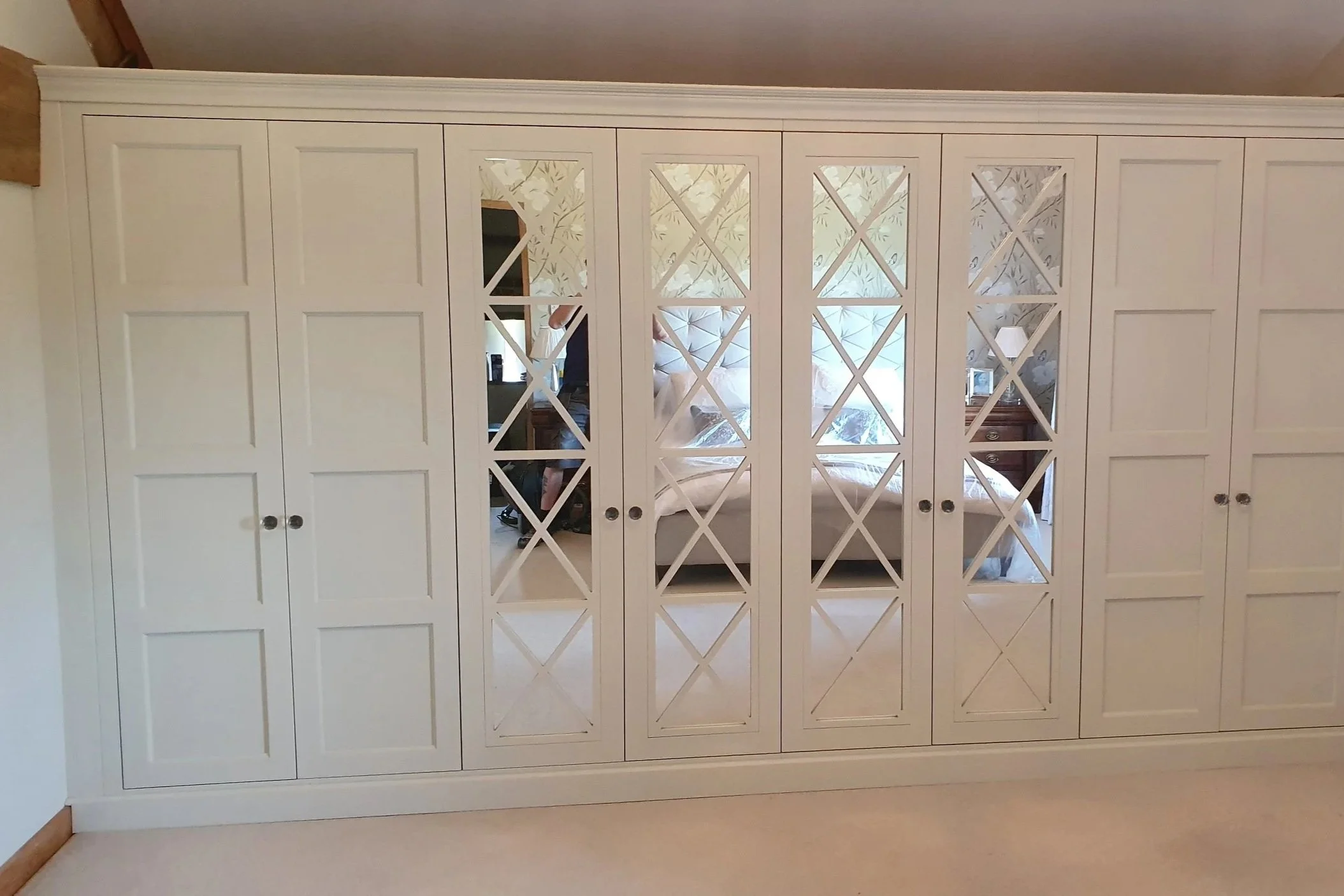 White wardrobe with lattice mirrored doors and square panelled doors.