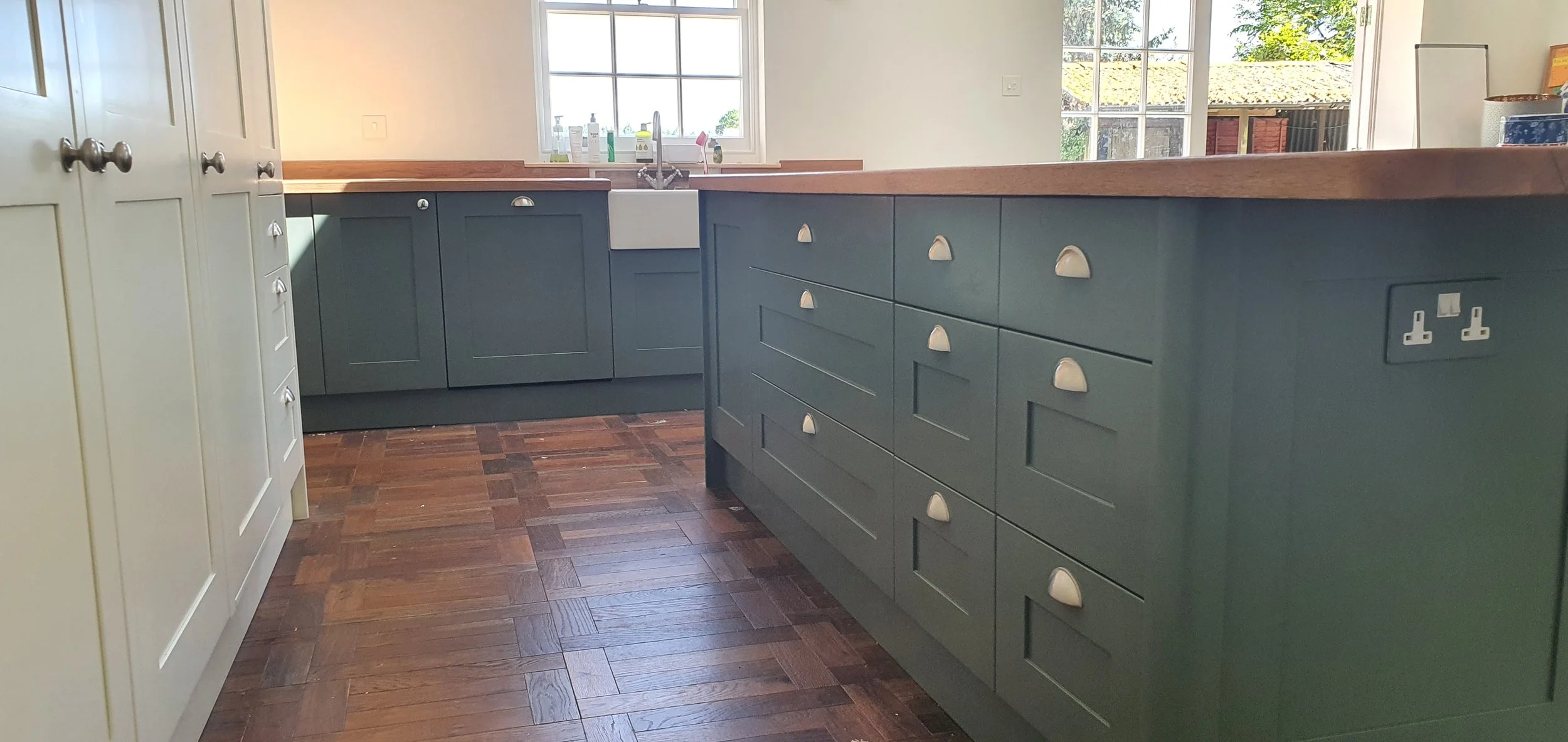 Large green painted kitchen island with lots of drawer storage and Oak worktop