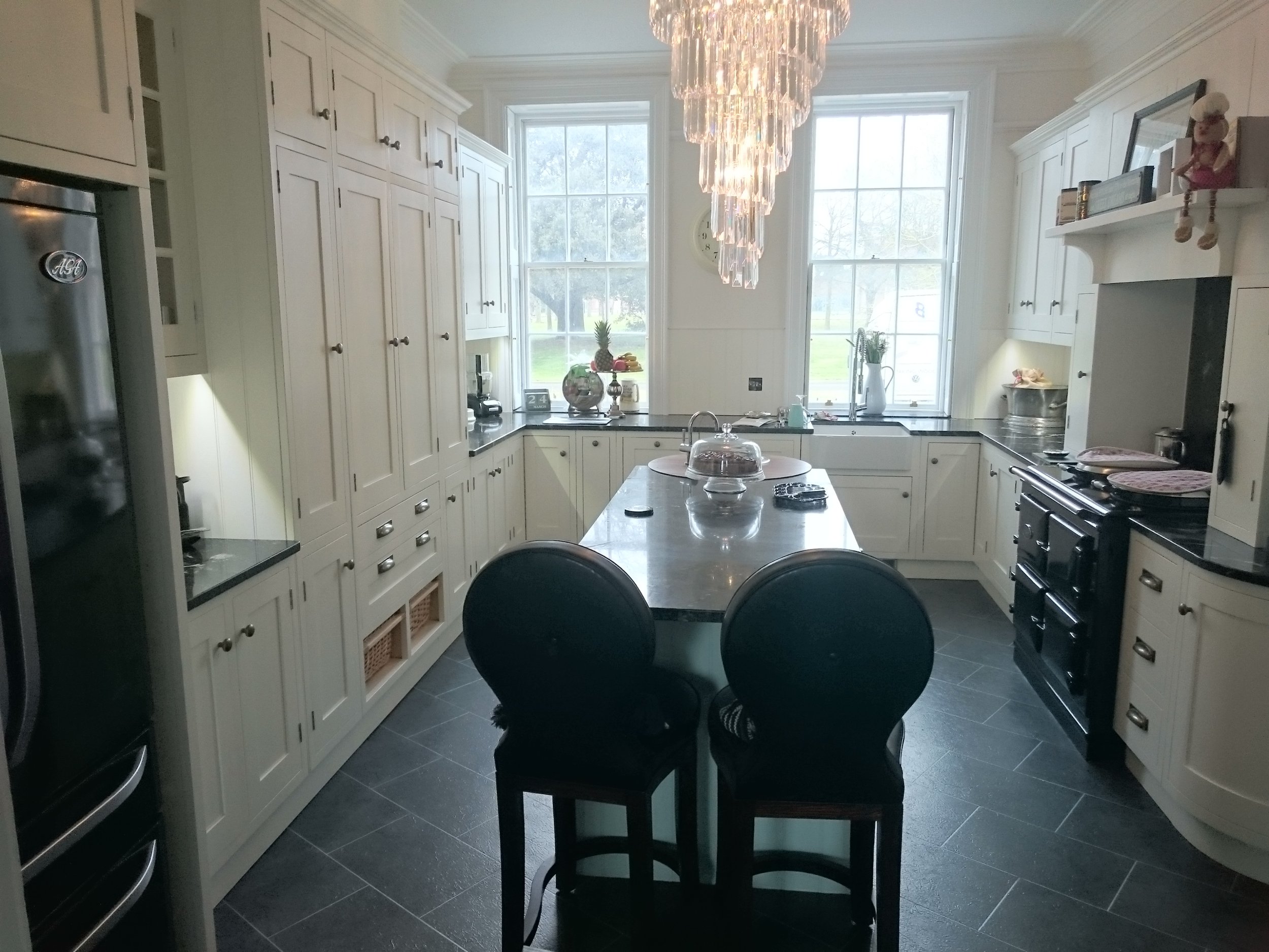 Large traditional painted kitchen with small curved kitchen island and black granite worktops