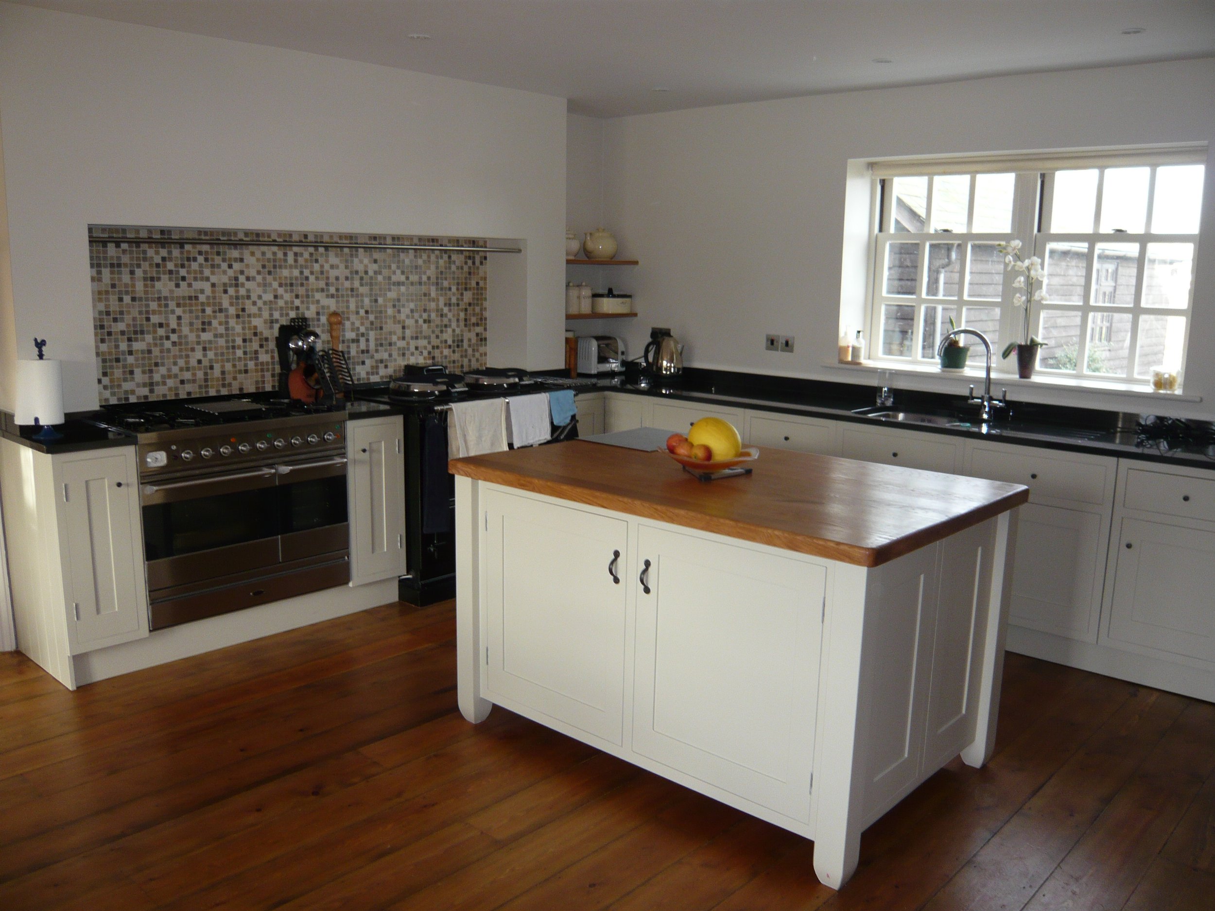 Traditional farmhouse style kitchen with range cooker black granite worktops and free-standing island with Oak worktops