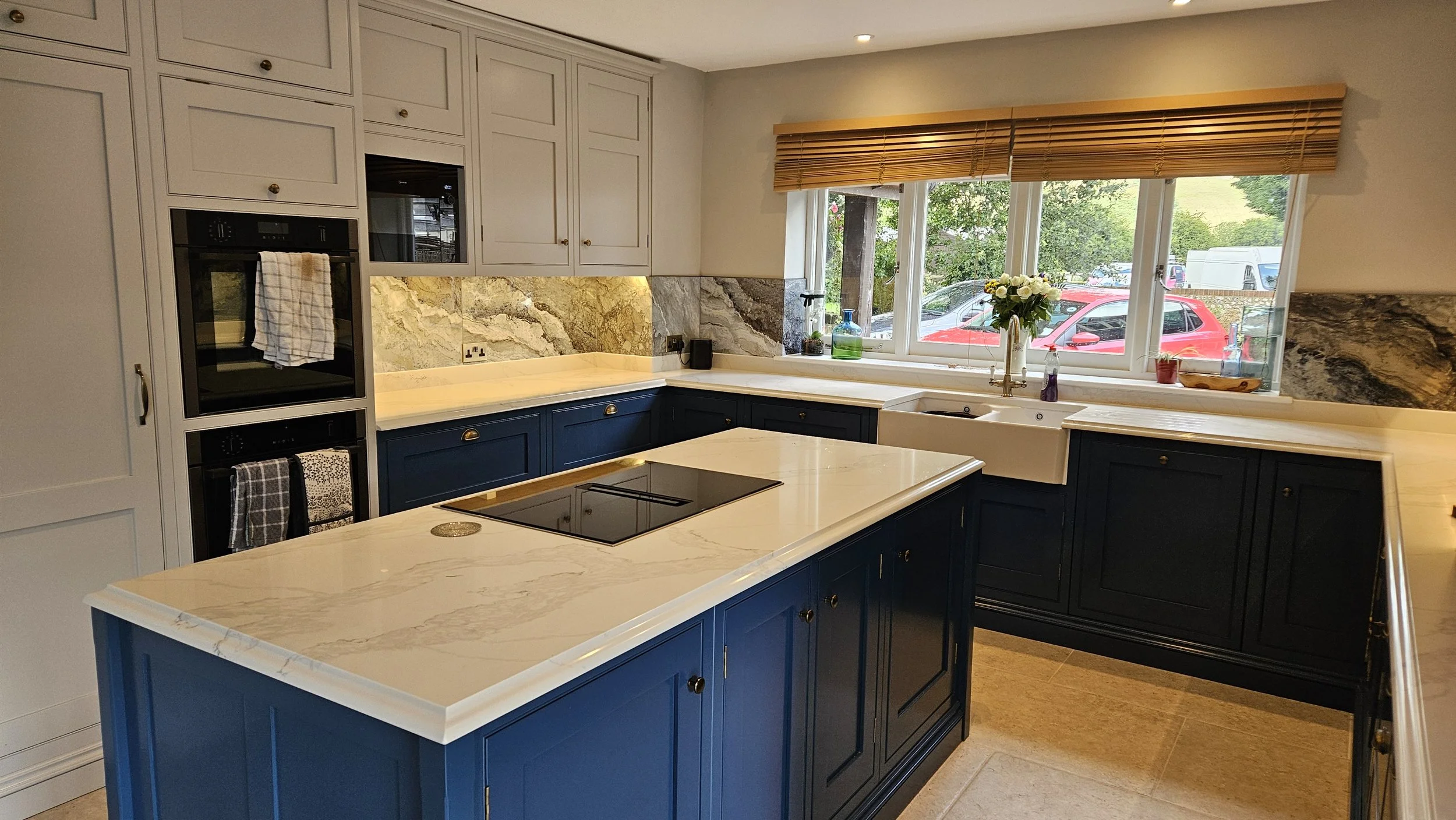 Traditional painted kitchen with cream wall units, dark blue base units and island with white stone worktops