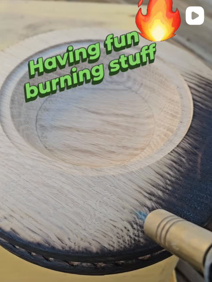 A wooden circular object being burned with a tool, with added text that says "Having fun burning stuff" and a fire emoji.
