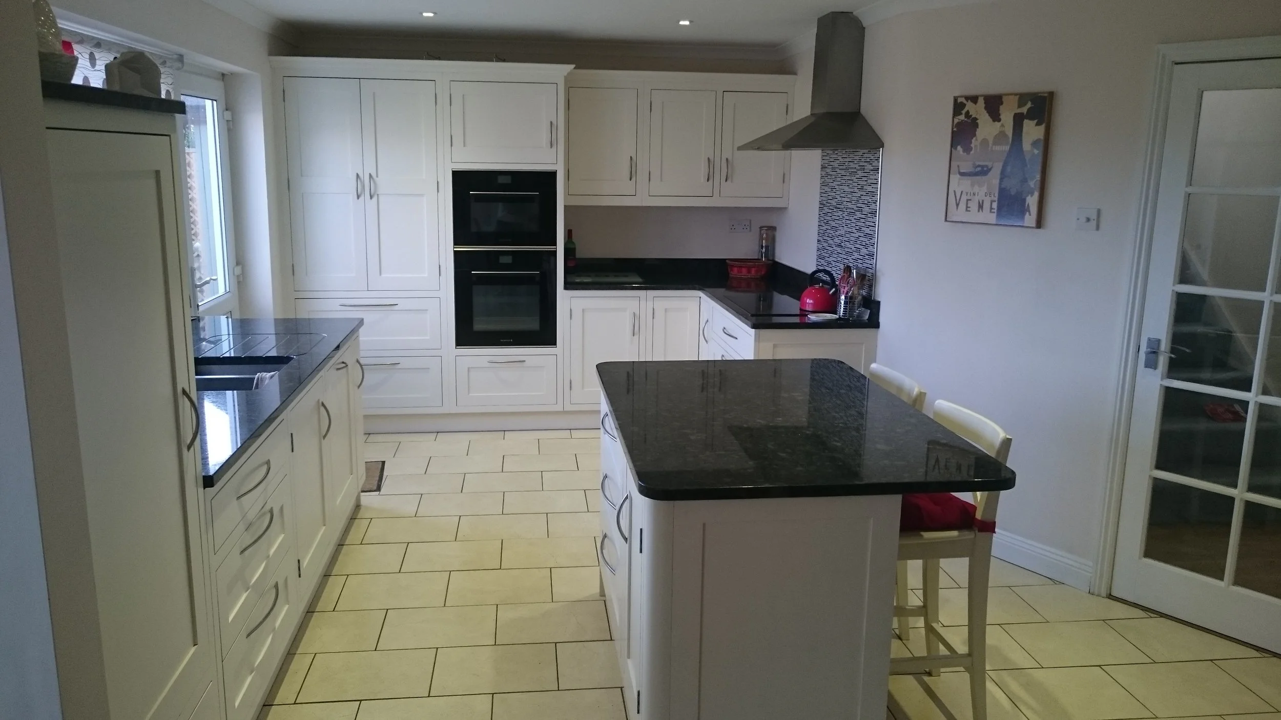 Cream traditional kitchen with small island and black granite worktops