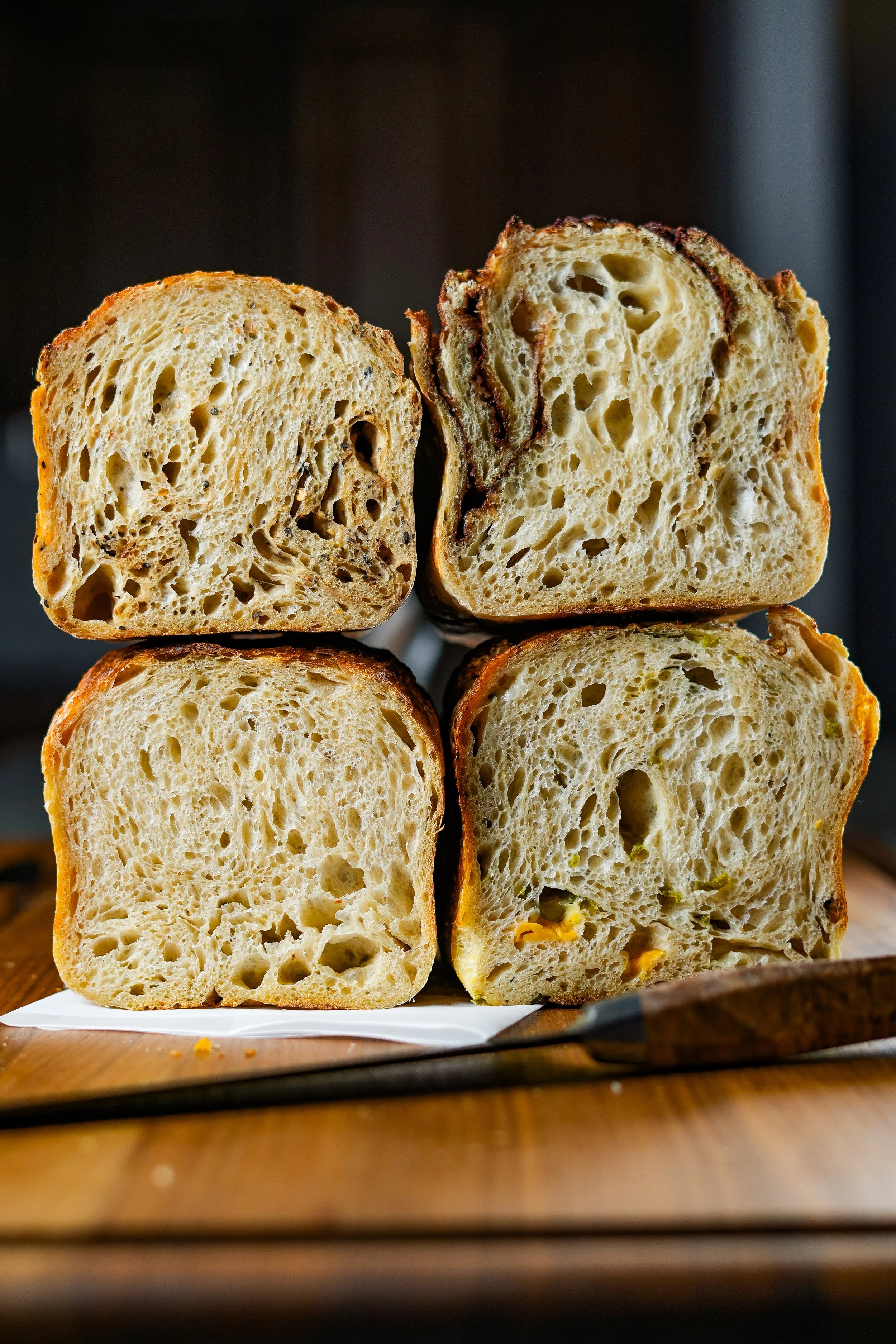 Stack of sliced bread with a rustic crust on a wooden surface.