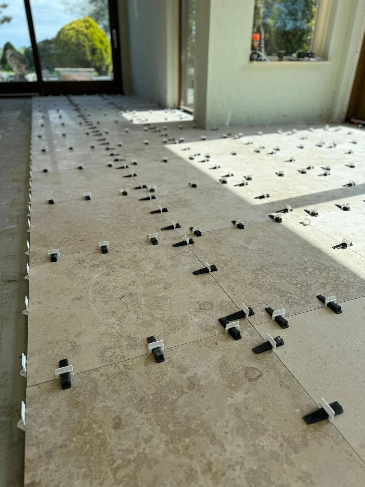 Binnenruimte met onderliggende tegels en verhogingsklemmen, mogelijk voor het leggen van vloertegels.