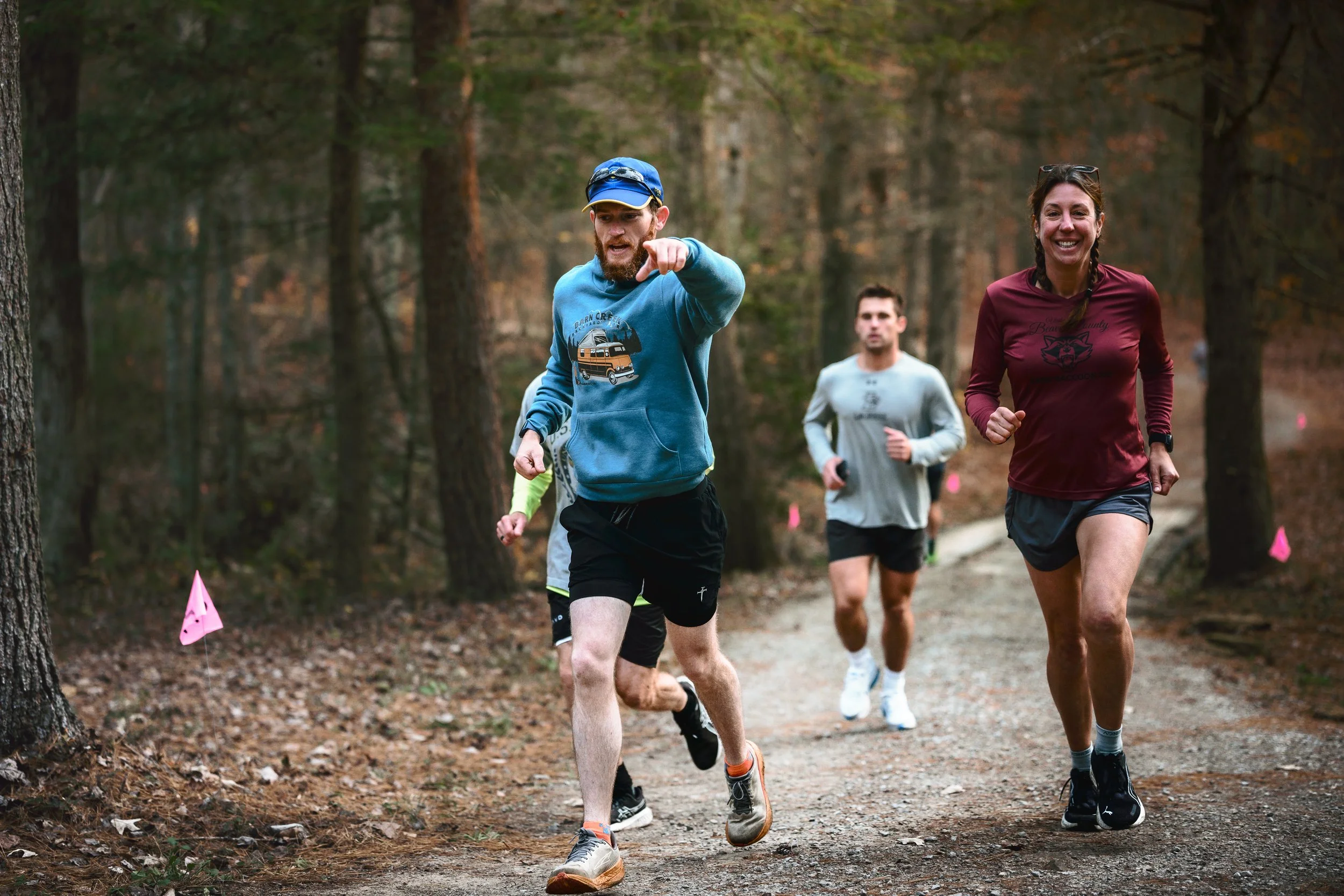 A group of runners jogging on a trail in a wooded area during daytime. Barn Creek Backyard Ultra