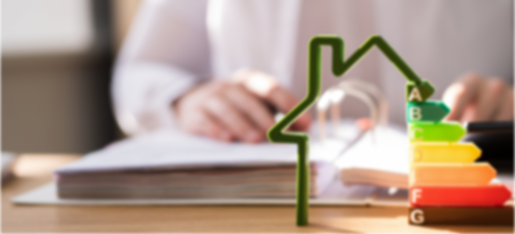 Eine Person arbeitet an einem Tisch mit Akten und bunten Energiesparlampen, die eine steigende Energieeffizienz darstellen.