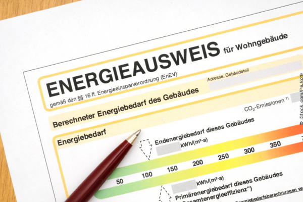 Energieausweis für ein Wohngebäude mit farbiger Skala und einem roten Stift.