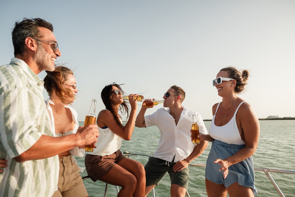 Group of five people enjoying beers while on a boat