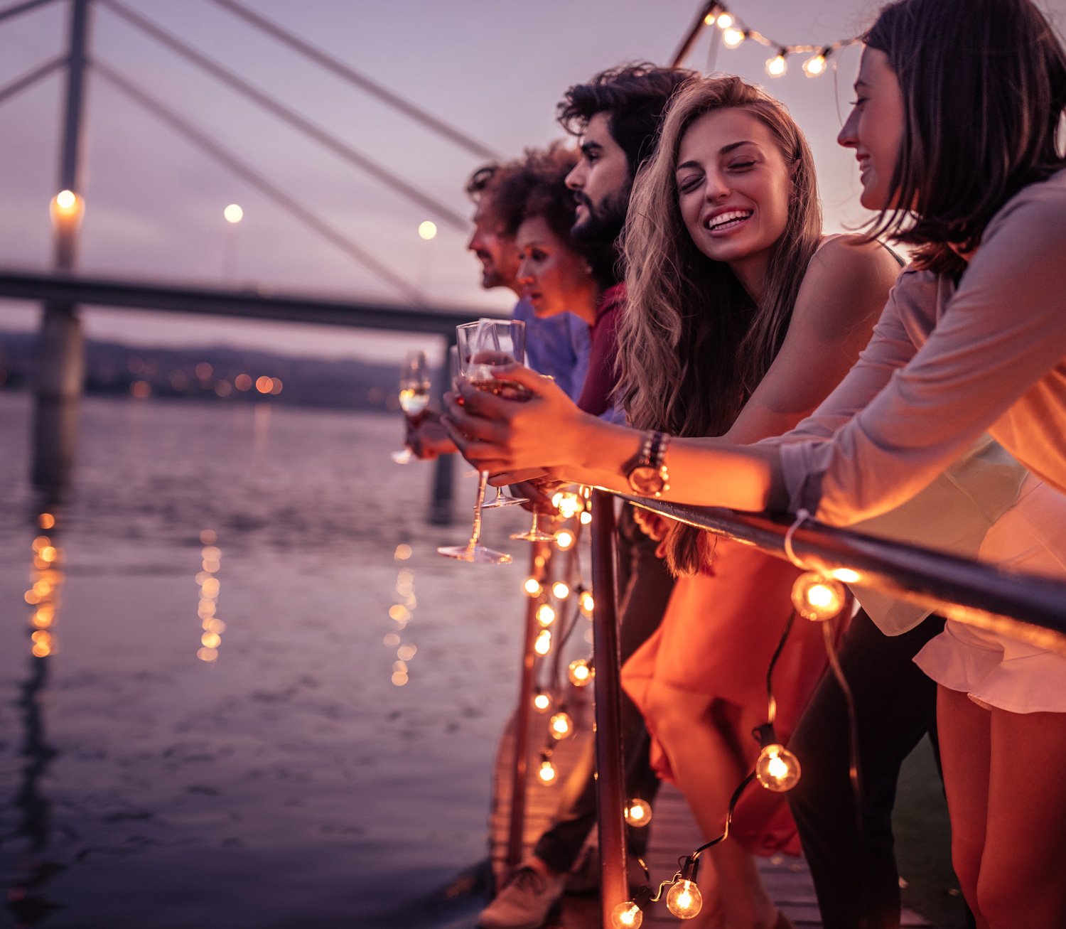Group of people looking at the water while on a boat holding drinks