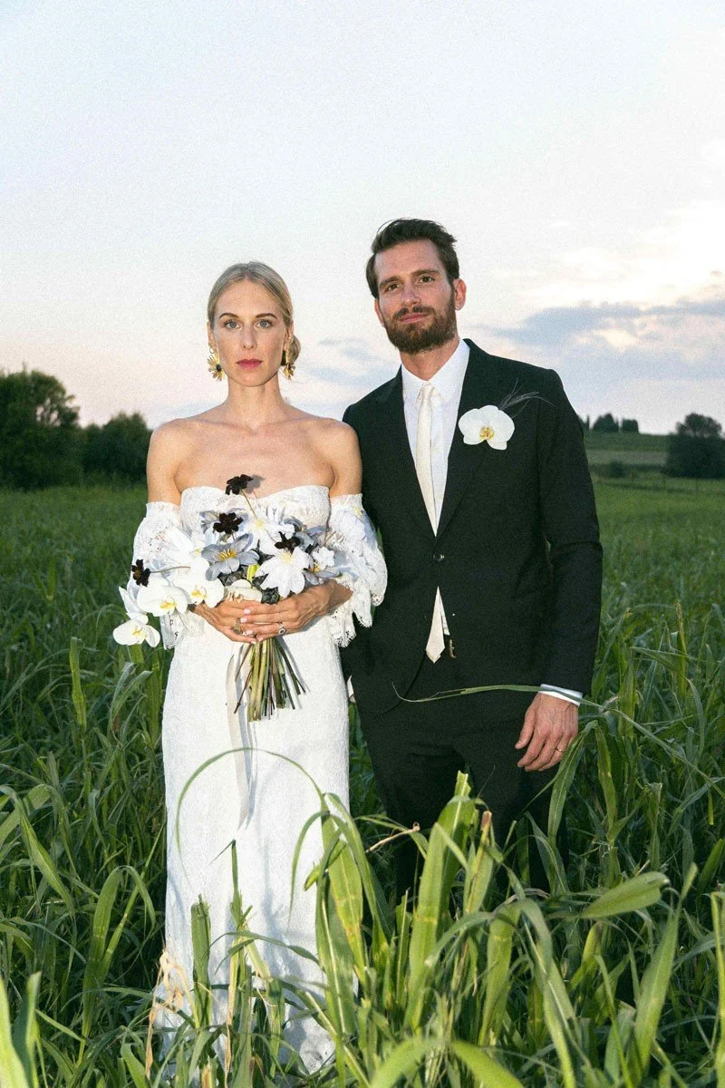 Una coppia in abiti eleganti da matrimonio posa in un campo di grano durante il tramonto.