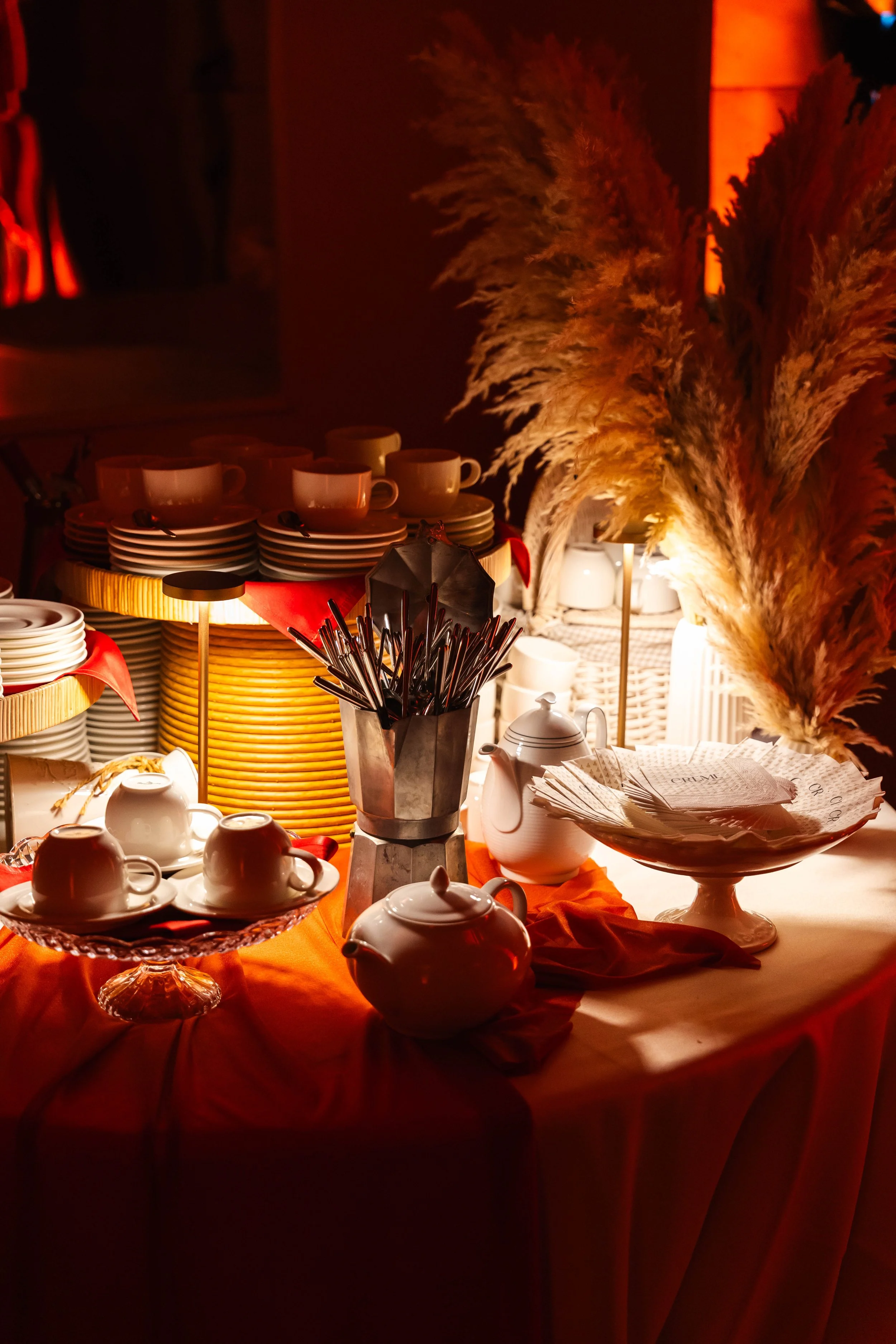 Lavagna con tazze, piatti, teiera, zuccheriera, e decorazioni di pampas grass in un ambiente caldo e accogliente.