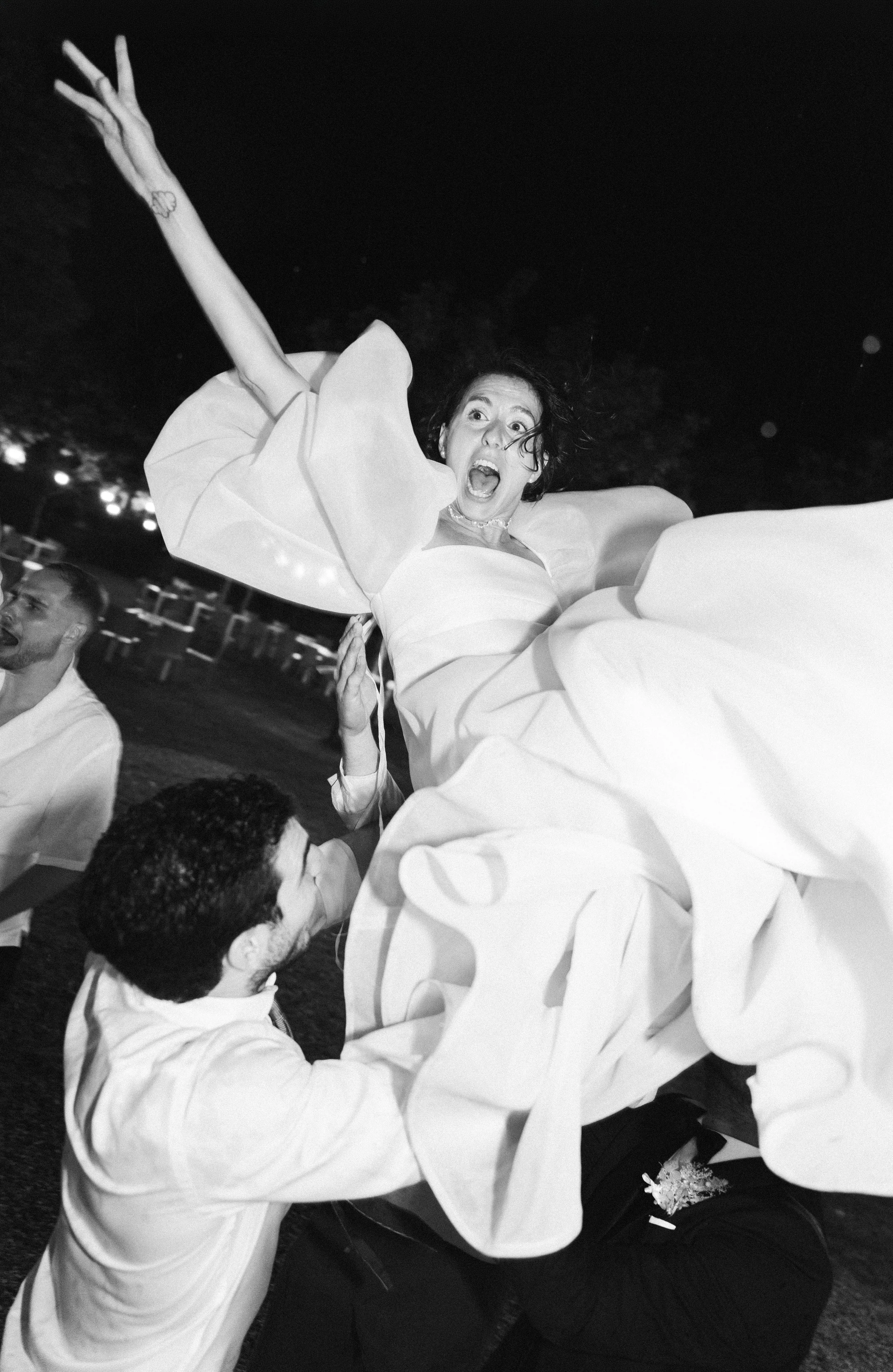Un gruppo di persone indossa abiti eleganti e sembra essere coinvolto in un'emozionante attività di festa all'aperto di notte, con una donna che grida e si diverte.