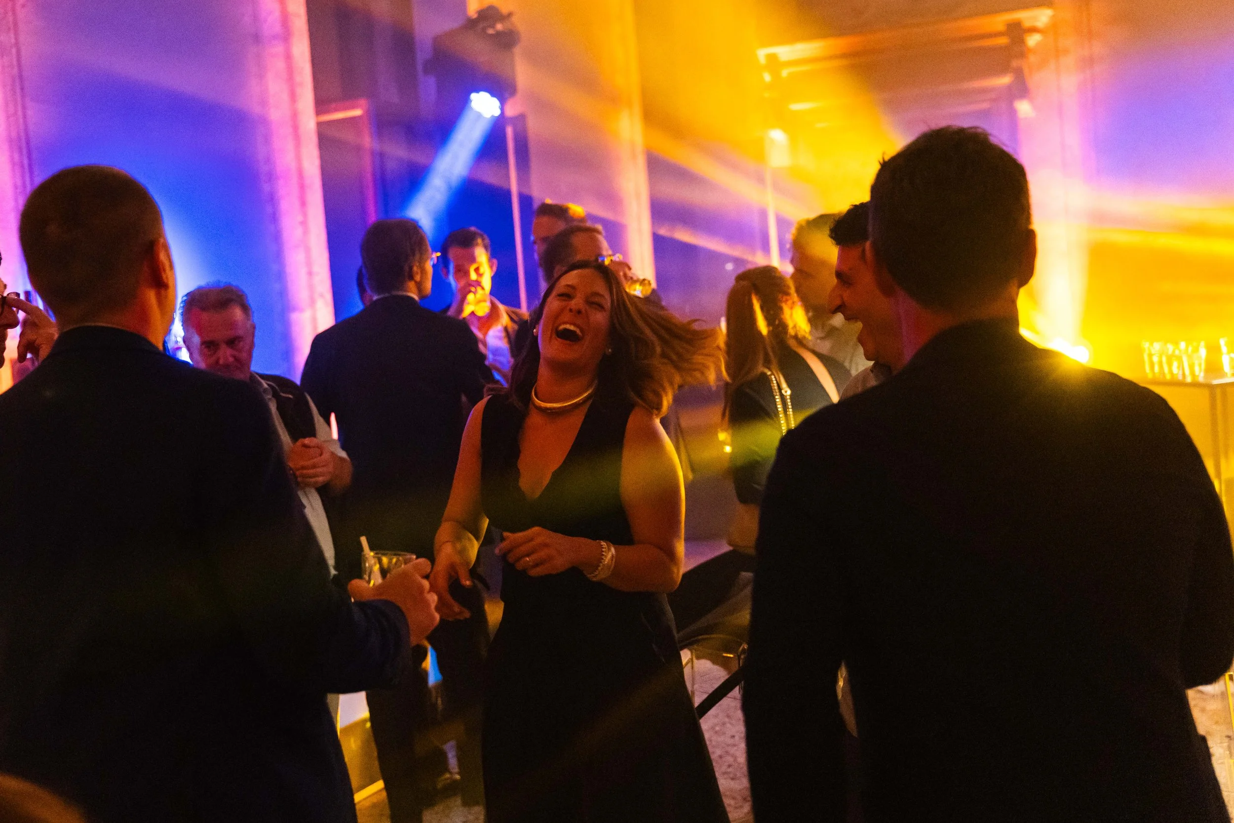 Persone che ridono e si divertono a una festa in un ambiente con luci colorate