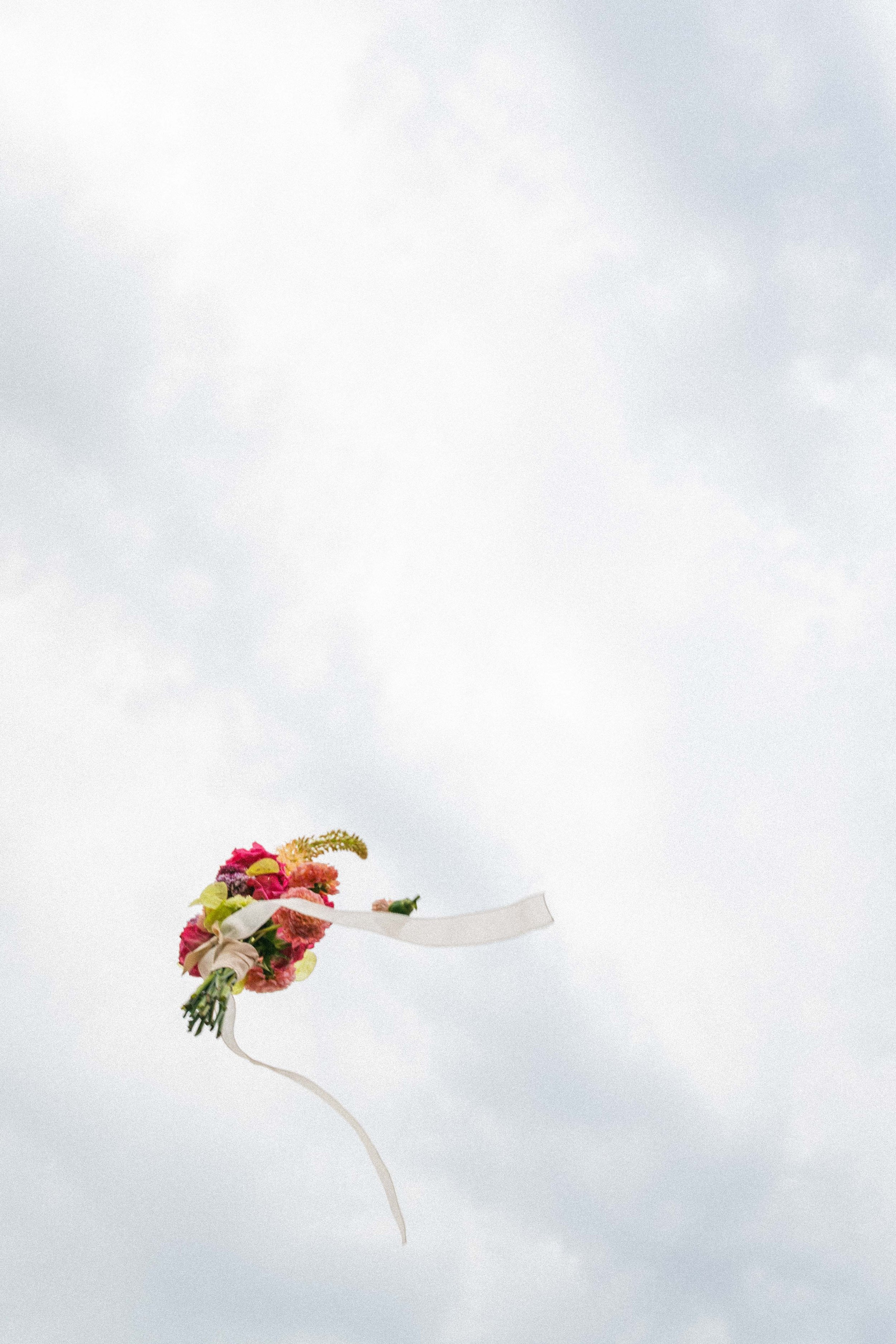 Un bouquet di fiori colorati con nastri di stoffa appeso nel cielo nuvoloso.