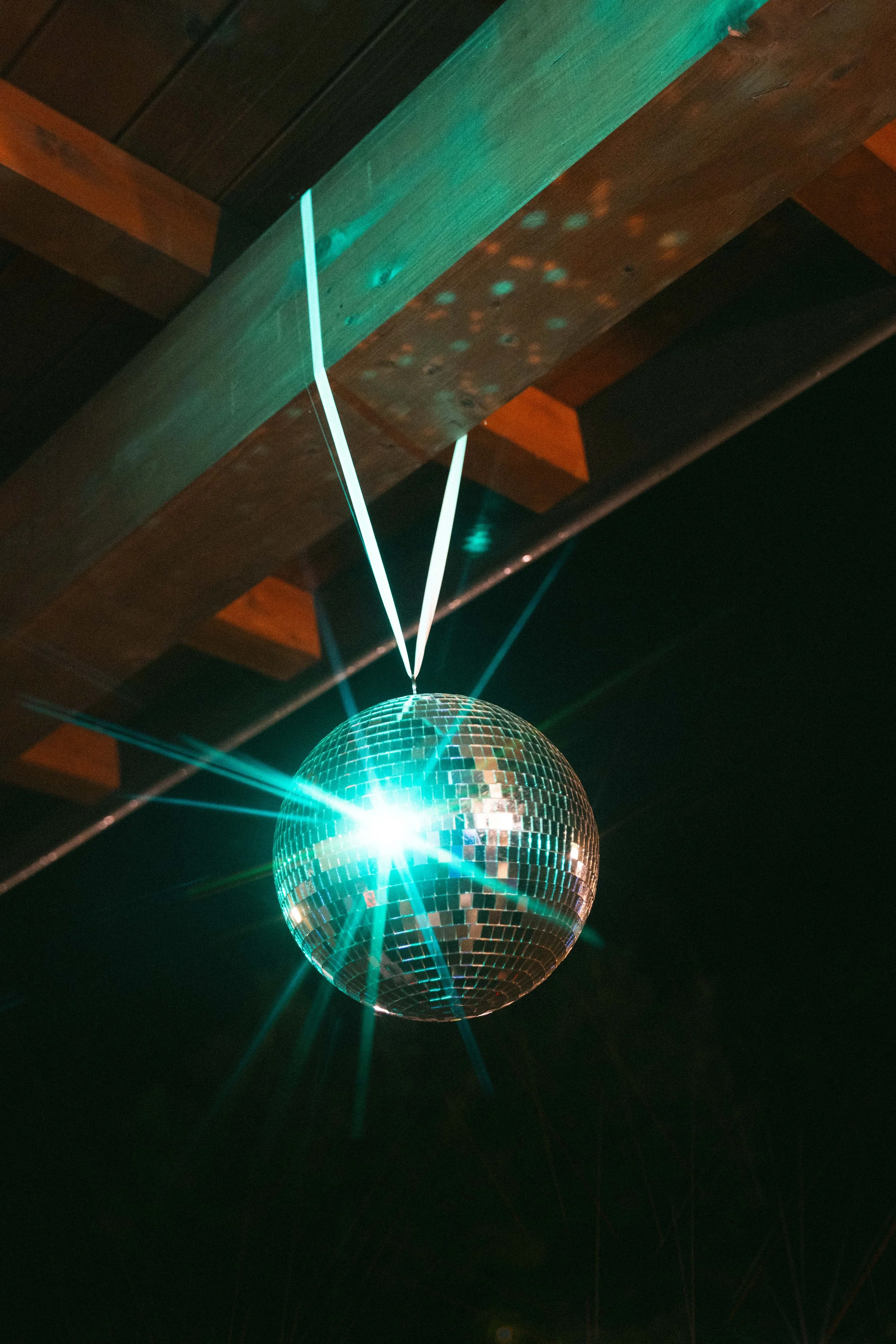 Palla da discoteca con luci colorate e riflessi, sospesa al soffitto con raggi di luce che riflettono sulla superficie.