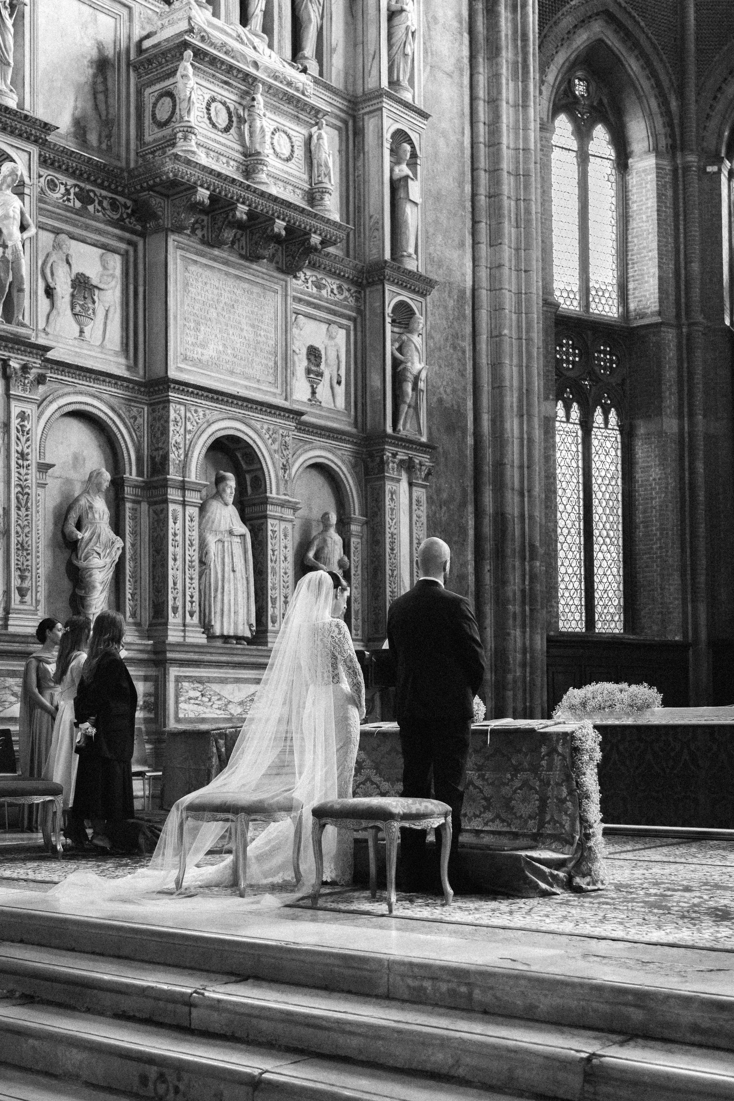 Un matrimonio che si svolge all'interno di una chiesa storica, con decorazioni barocche e statue religiose, durante la cerimonia.