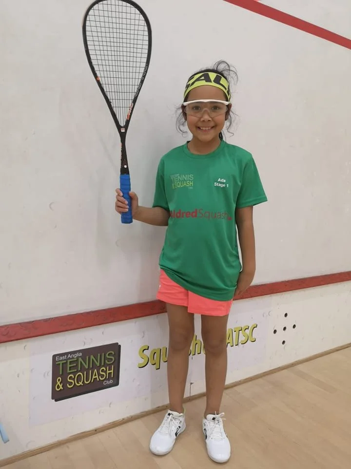 Young squash player smiling and holding racket up