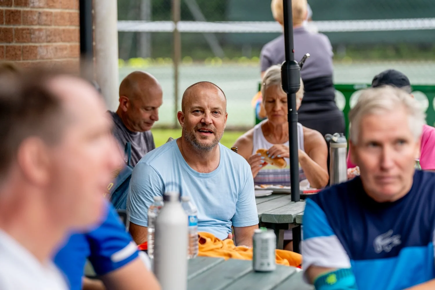 Group of players recovering outside in the sunshine having a drink and something to eat