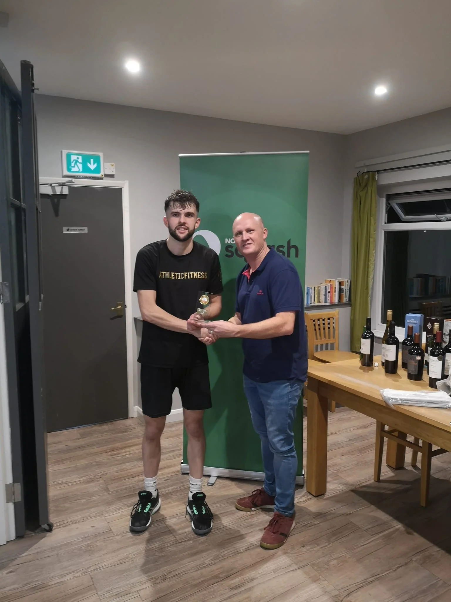 Male squash player being present award by club chairman Herman