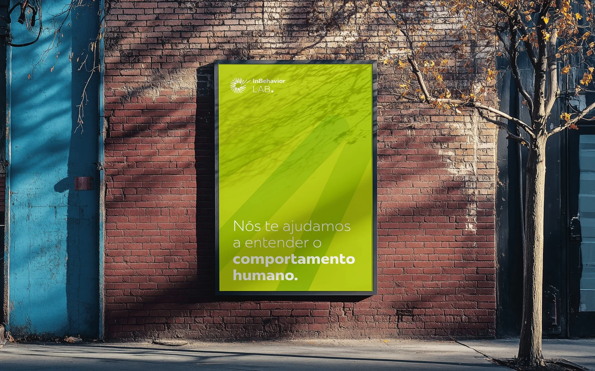 Outdoor outdoor poster on a brick wall with green background and white text, next to a leafless tree.