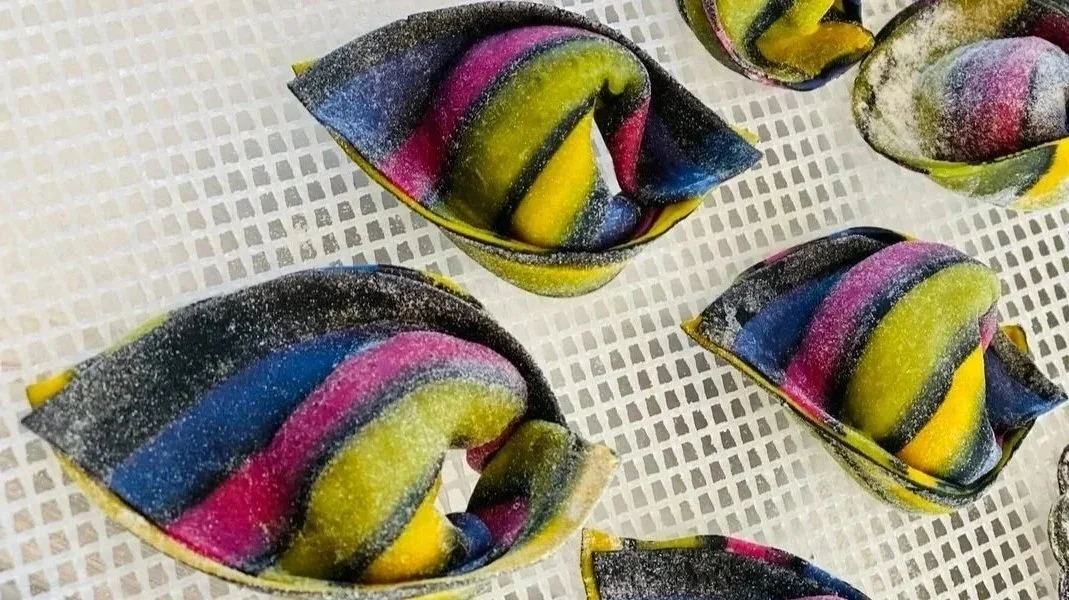 Colorful, striped pasta dough placed on a drying rack.