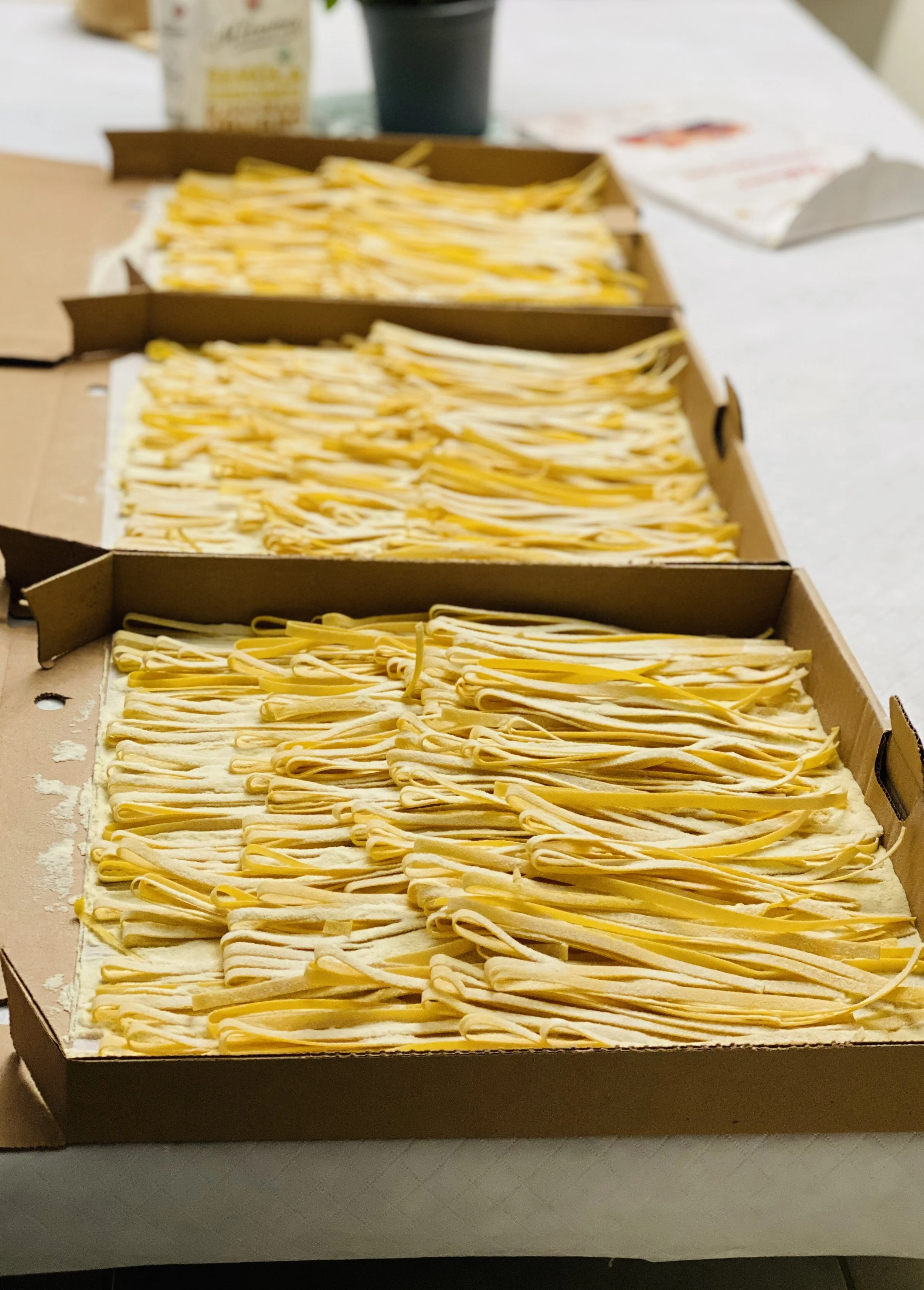 Three open boxes of uncooked Long pasta on a table.