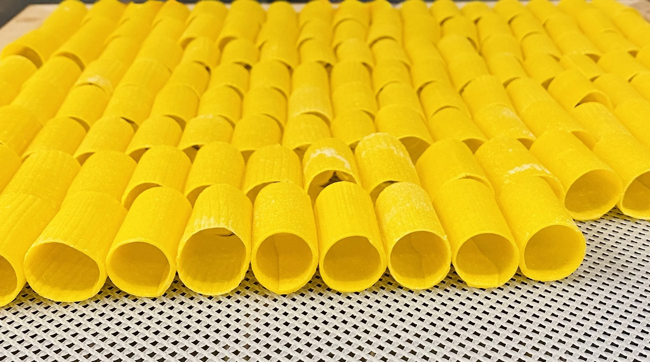 Pasta noodles arranged in a grid pattern on a textured surface.