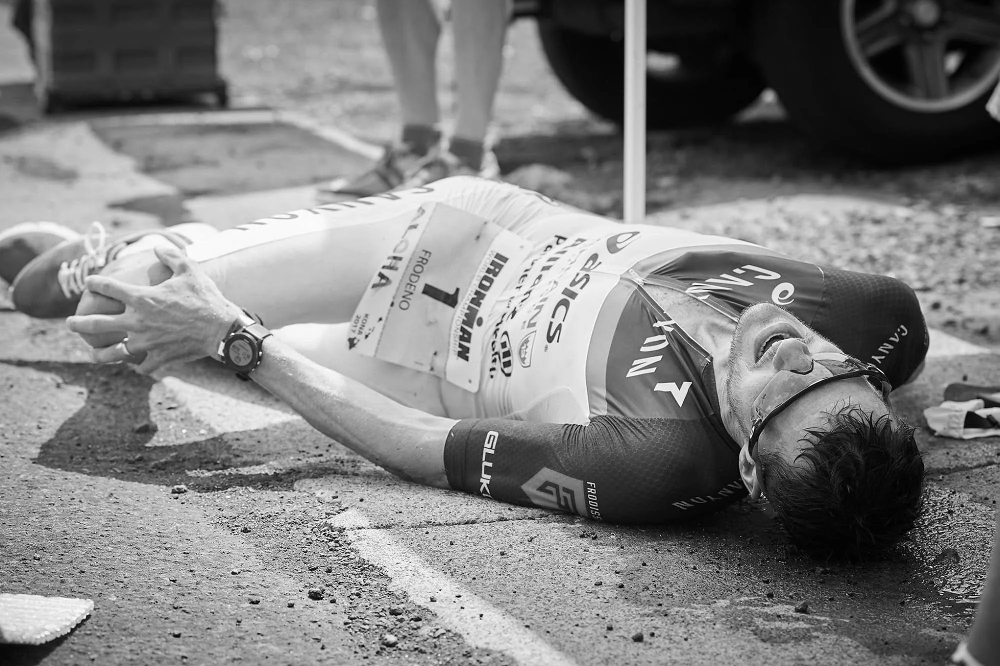 Jan Frodeno lies on the ground with his hands clasping his knee in the 2019 Kona Ironman World Championships
