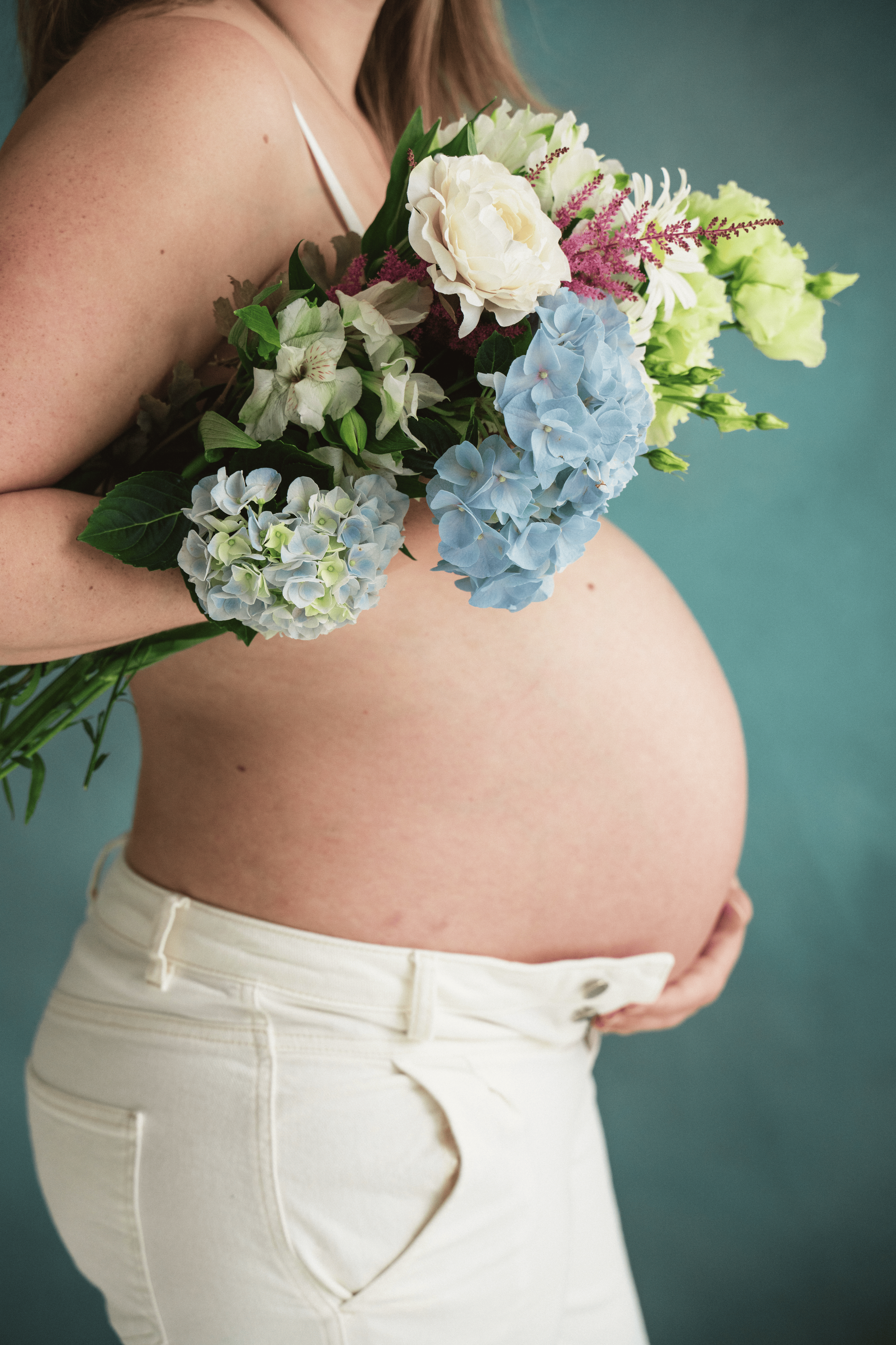 Foto: Cecilie Hatløy, Møre Media AS. Nærbilde av en gravid kvinne som holder en bukett med blomster.